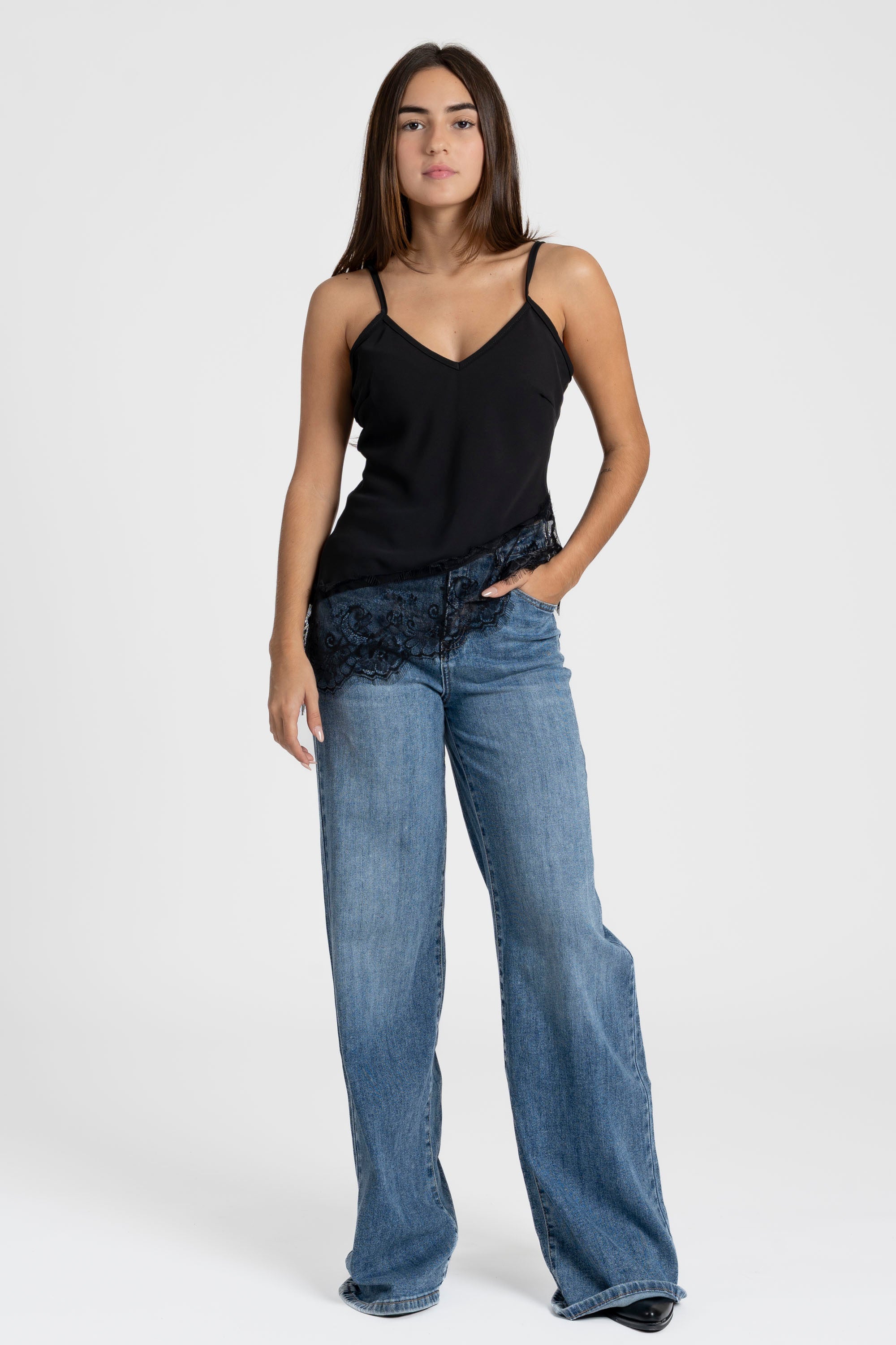 Top dentelle noir avec bretelles fines et décolleté en V, stylé avec un jean ample.