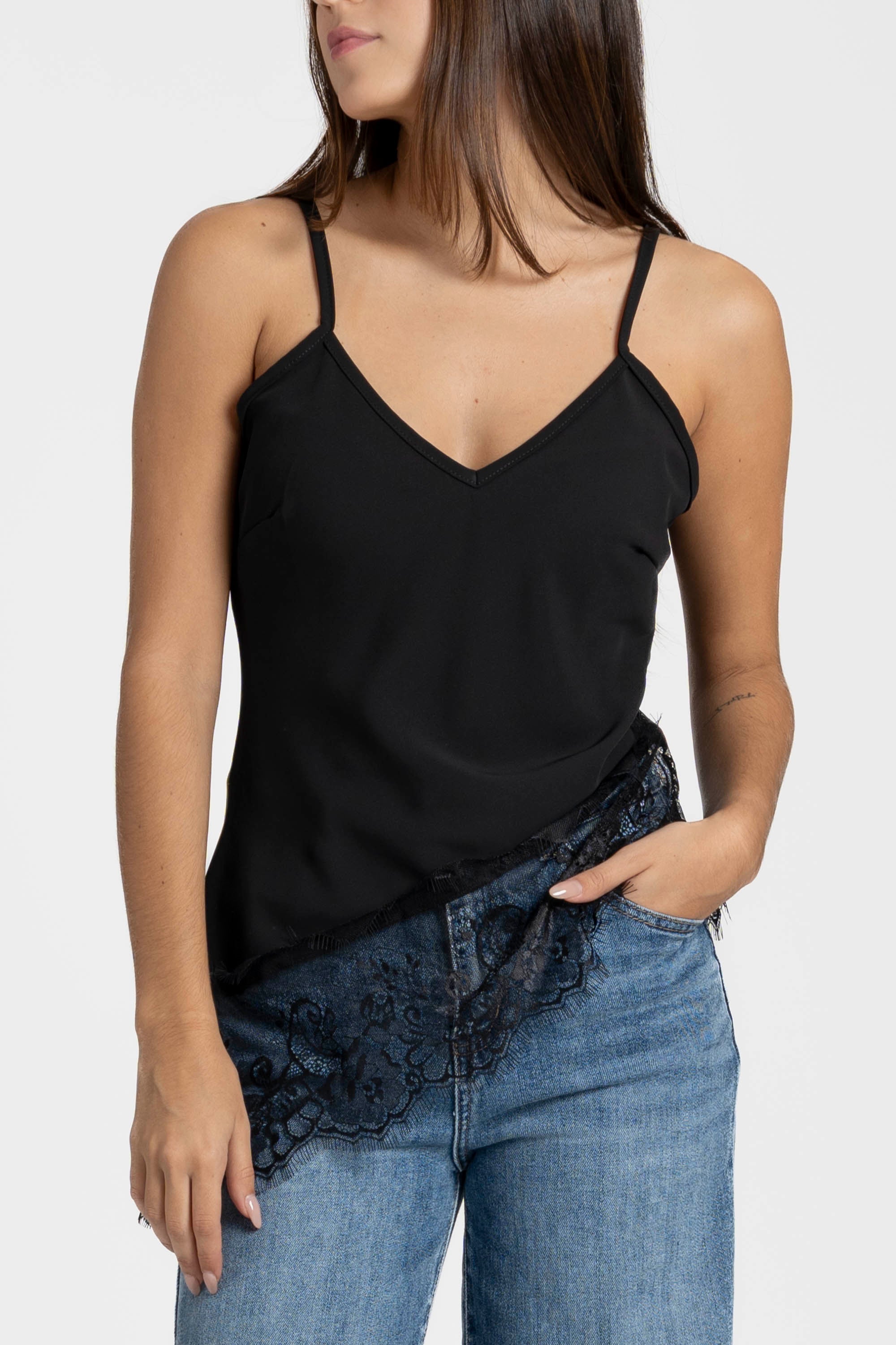 Détail du top dentelle noir, décolleté en V et dentelle délicate visible sur le jean.