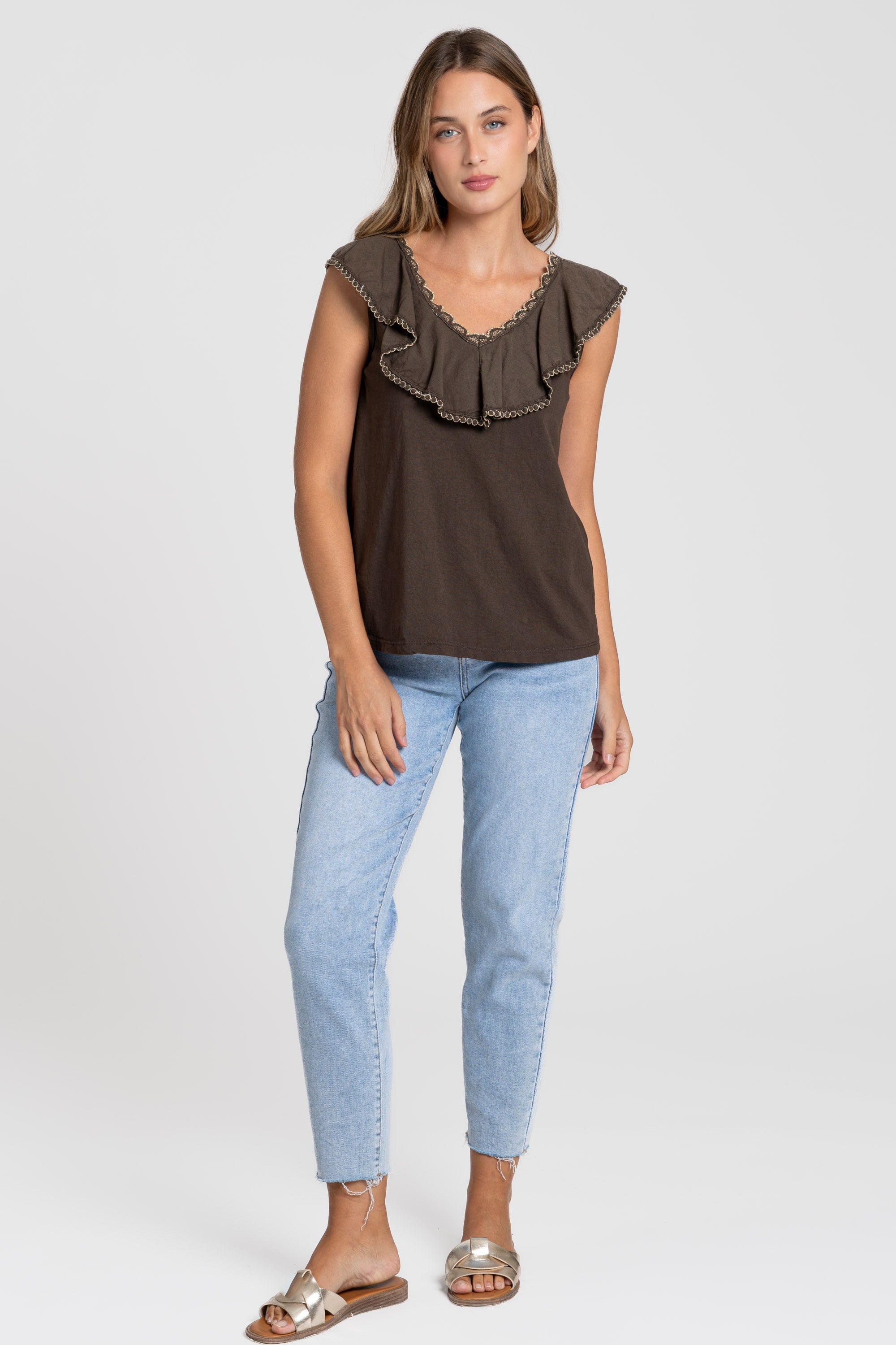 Femme souriante portant le Top coton brodé beige avec volants, parfait pour une tenue quotidienne ou de soirée.