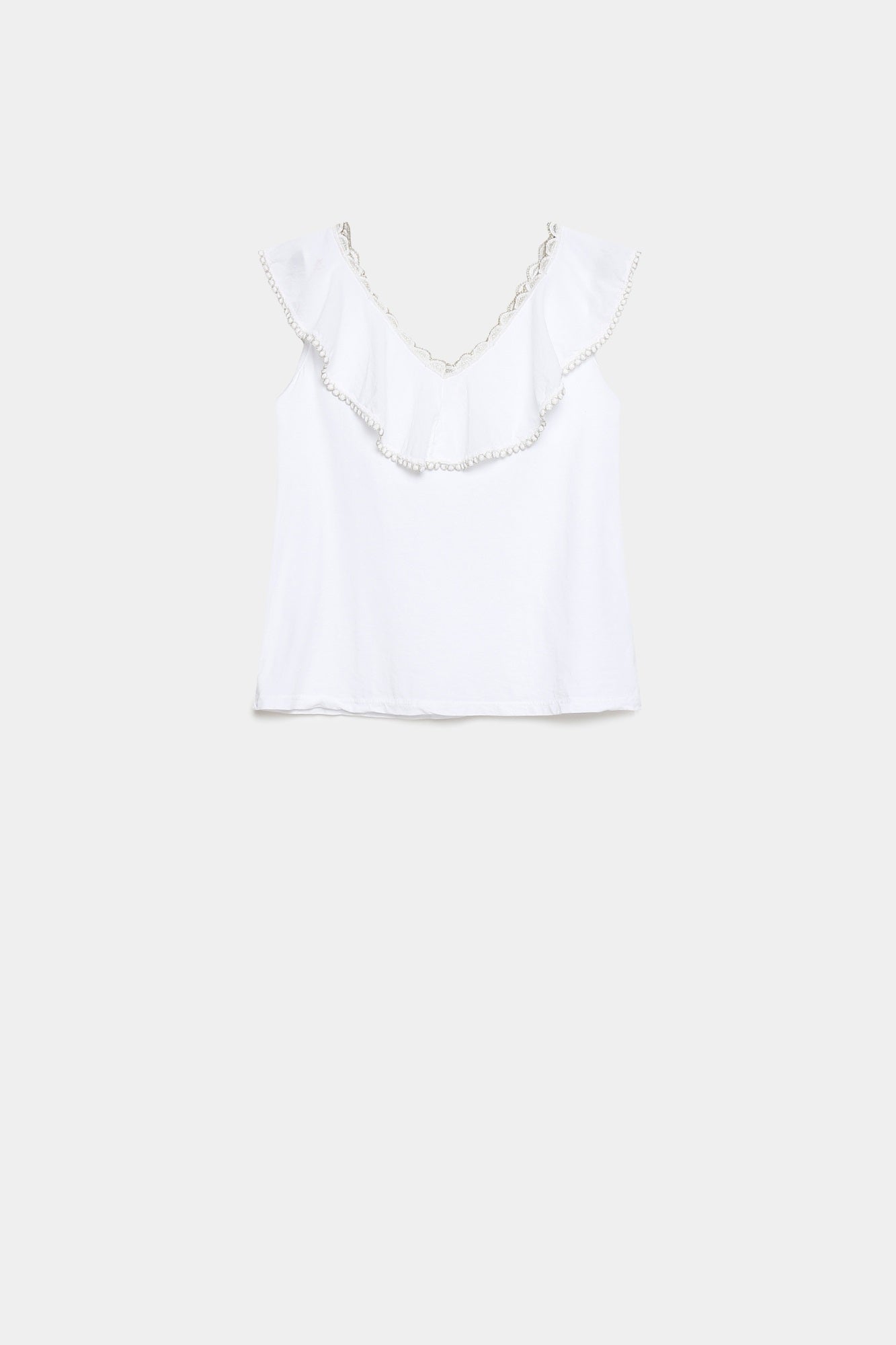Top coton brodé volants femme en blanc, exposé à plat pour montrer son allure élégante et simple.