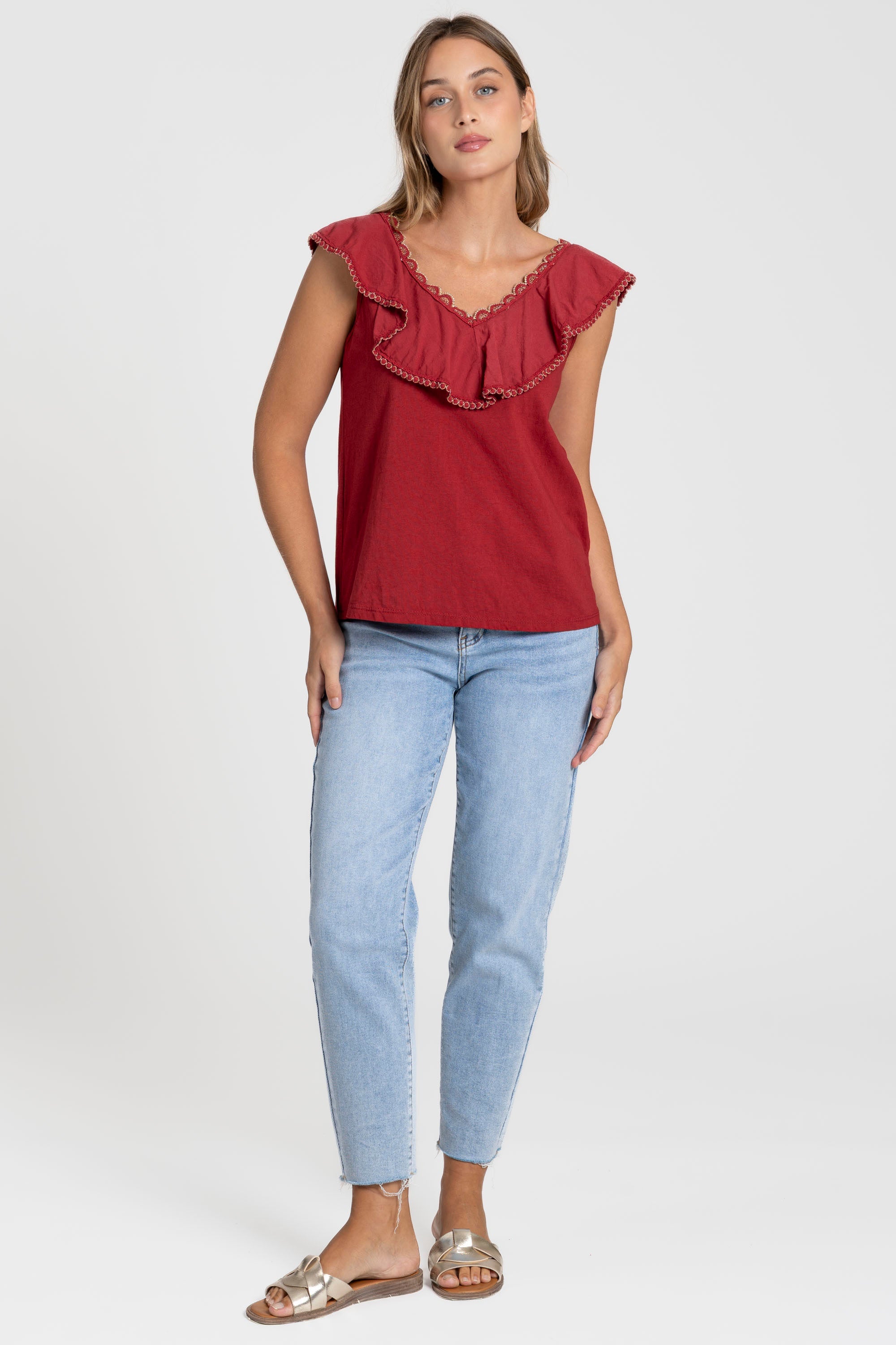 Femme avec un look décontracté portant le Top coton brodé volants femme col V sans manches en rouge.