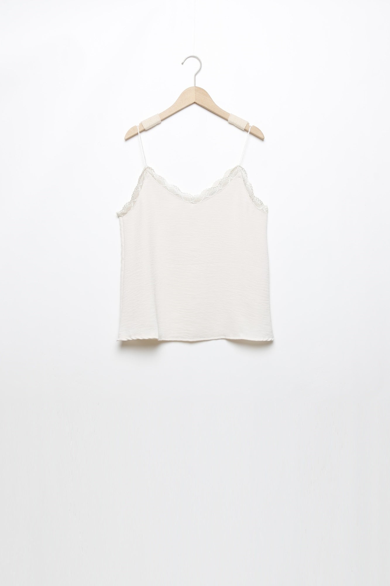 Top en mousseline femme fluide à bretelles avec dentelle blanche suspendu, mettant en avant sa coupe moderne.