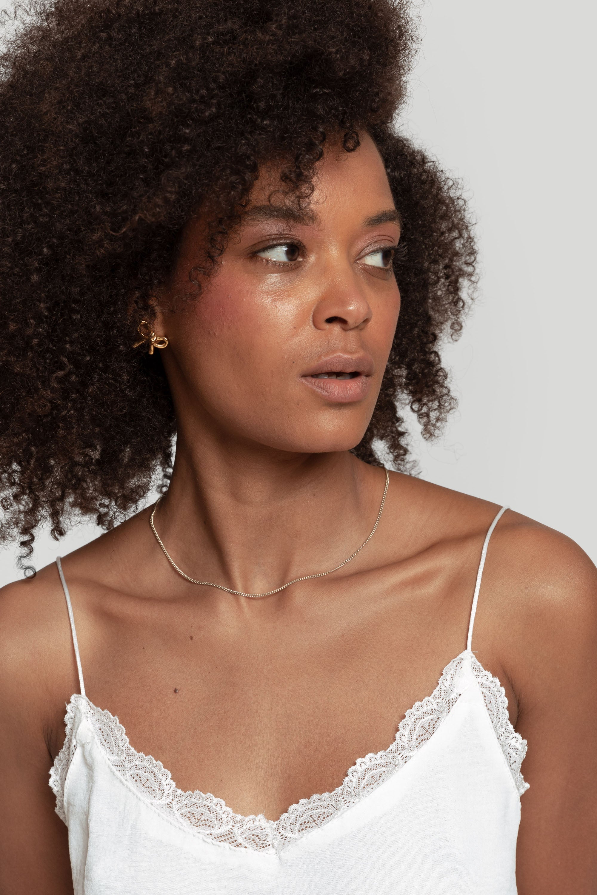 Détail du visage d'une femme avec le top en mousseline femme fluide à bretelles avec dentelle blanche, regard naturel.