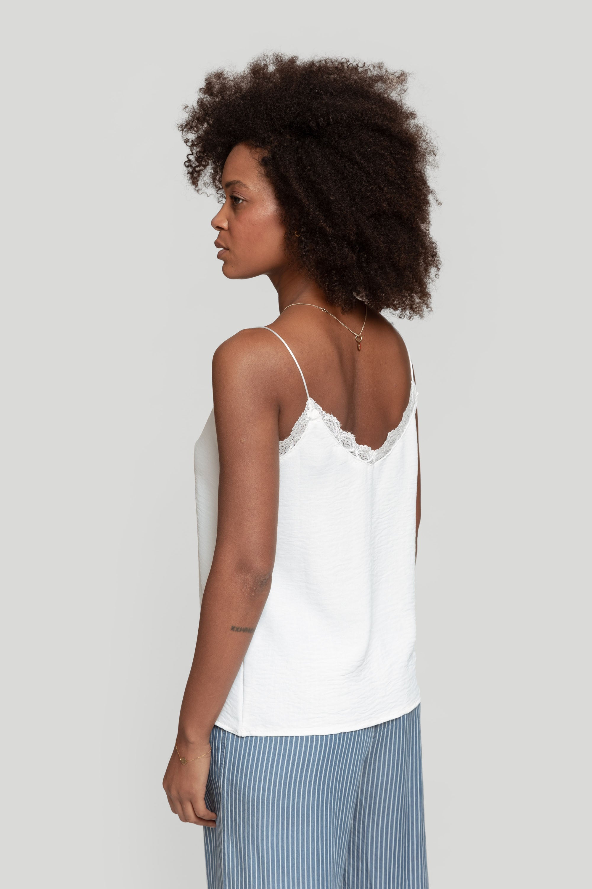 Profil d'une femme portant le top en mousseline femme fluide à bretelles avec dentelle blanche, simple et chic.