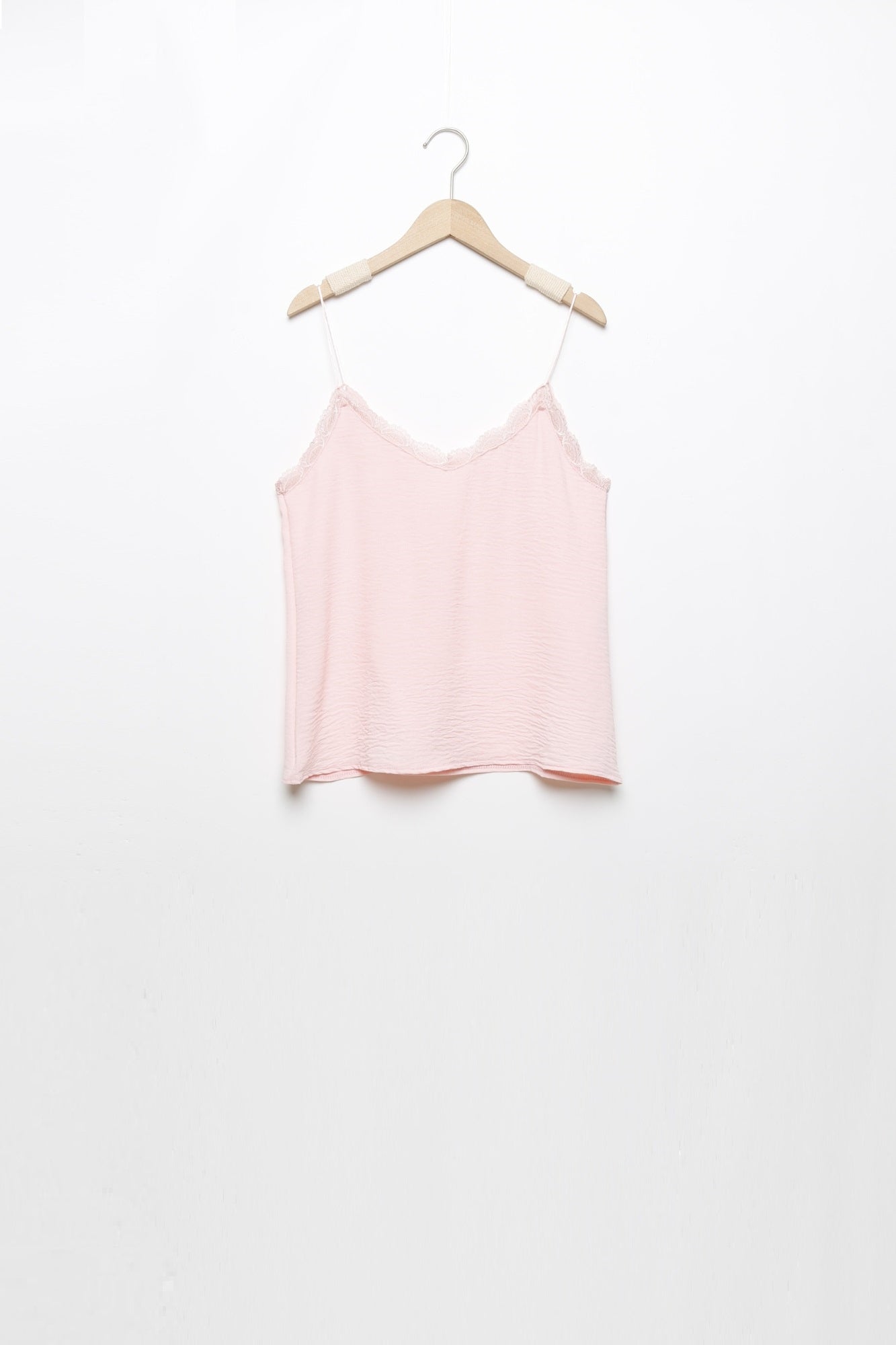 Top en mousseline femme fluide à bretelles avec dentelle rose, suspendu, prêt à être ajouté à la garde-robe.