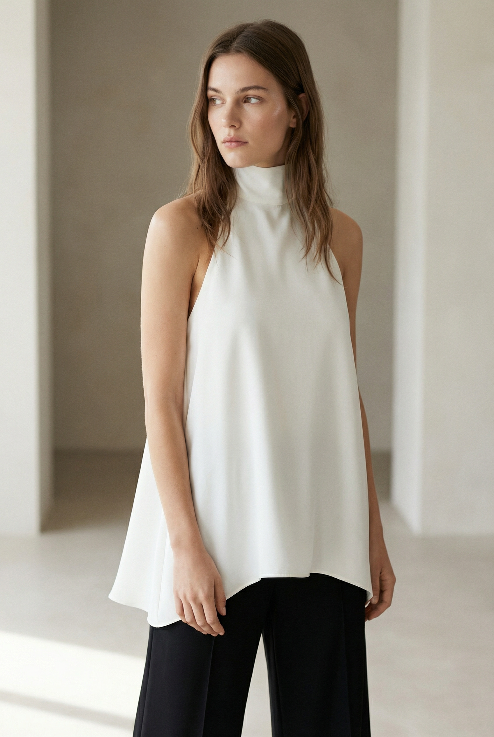 Portrait d'une femme en haut chic écru, stylé et épuré, dans un environnement minimaliste.