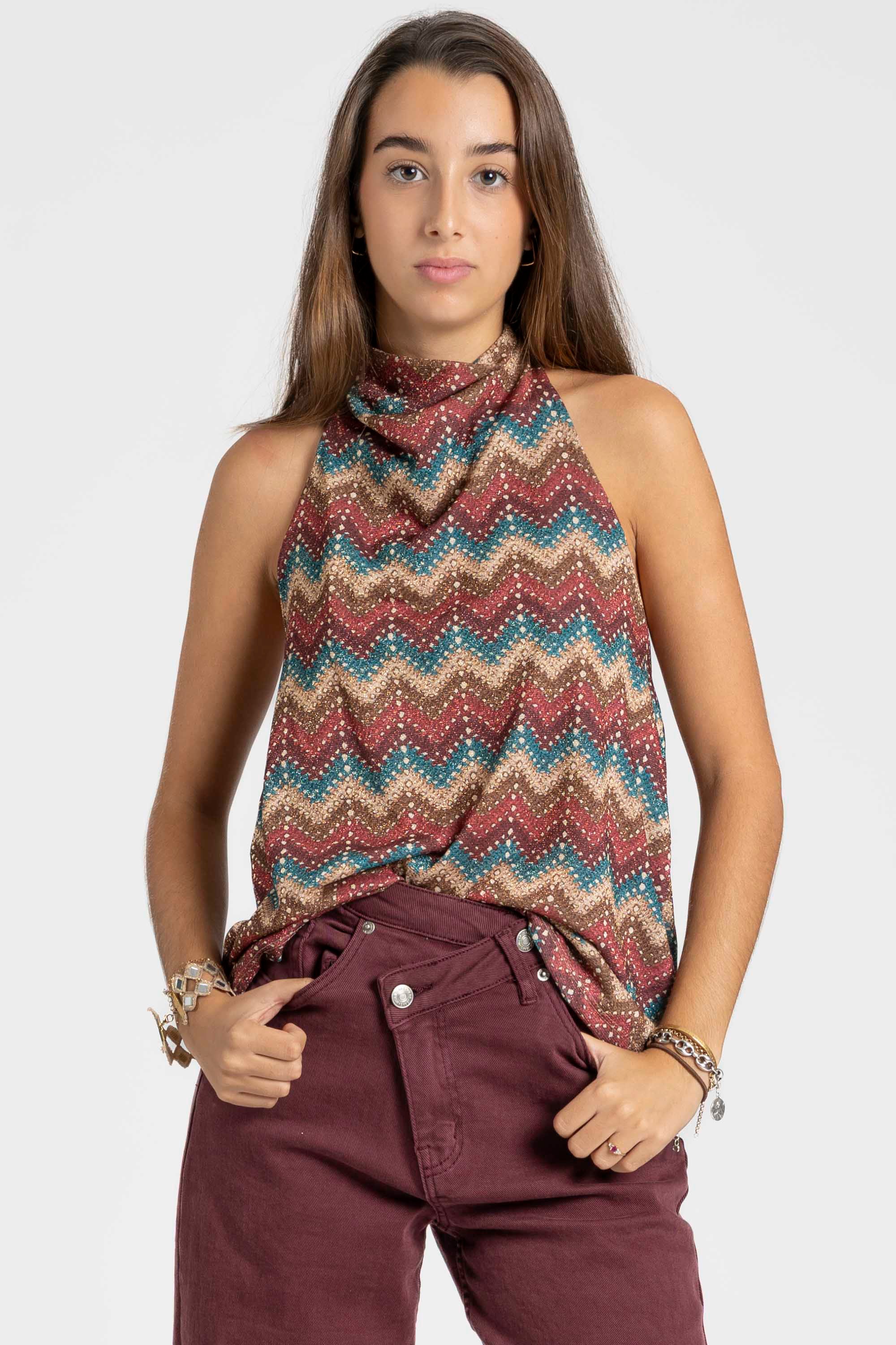 Top halter imprimé femme porté par une modèle au style coloré, associé à un pantalon bordeaux.