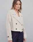 Modèle en portrait portant un trench coat court femme beige à double boutonnage, mettant en valeur la silhouette et le style contemporain.