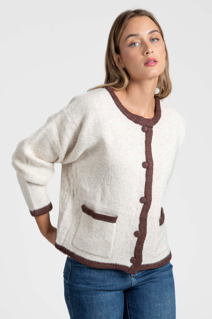 Veste en maille contrastée chic – Coupe droite – Beige ou gris – Maille laine mélangée, détail d'une femme affichant une pose naturelle, les poches visibles.