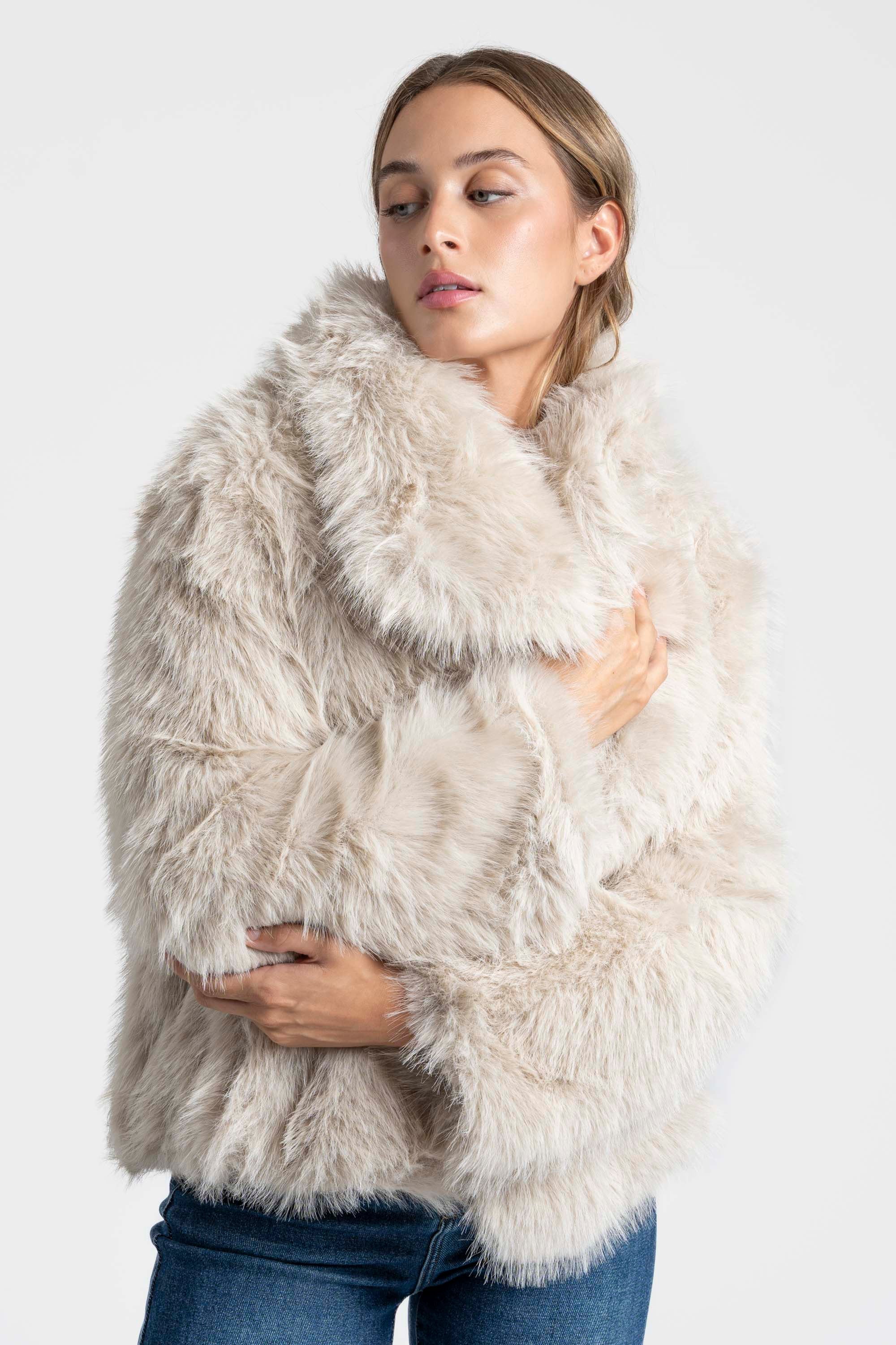 Modèle féminin vêtu d'une Veste fausse fourrure beige, avec un col ample, idéale pour une tenue chic et décontractée.