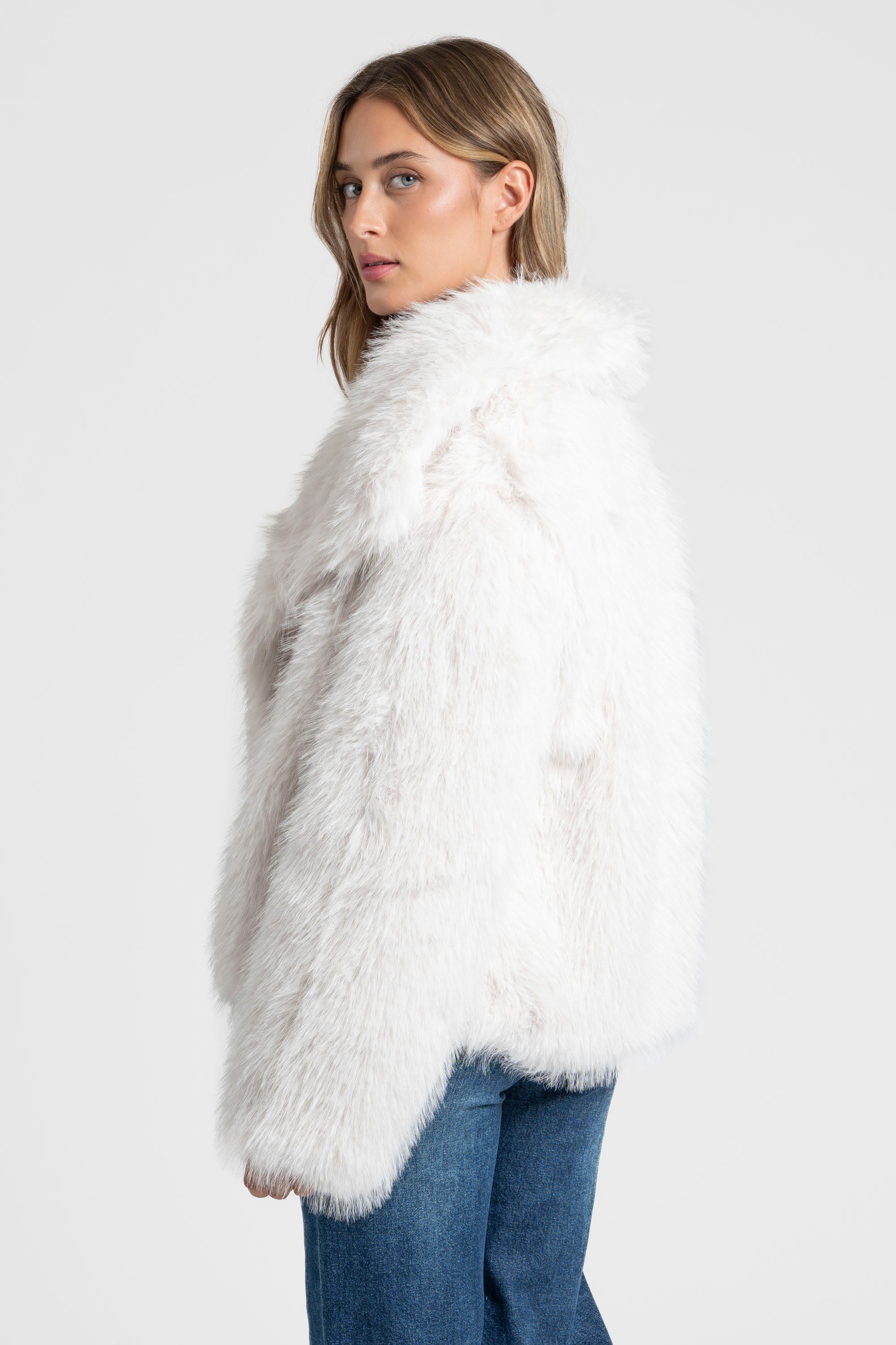 Modèle féminin en Veste fausse fourrure blanche, offrant un style confortable et sophistiqué.