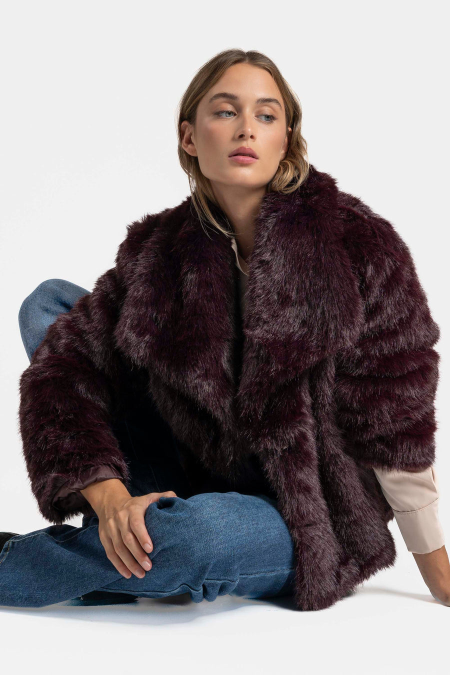 Femme dans une Veste fausse fourrure bordeaux, offrant une esthétique automnale séduisante avec un look décontracté.