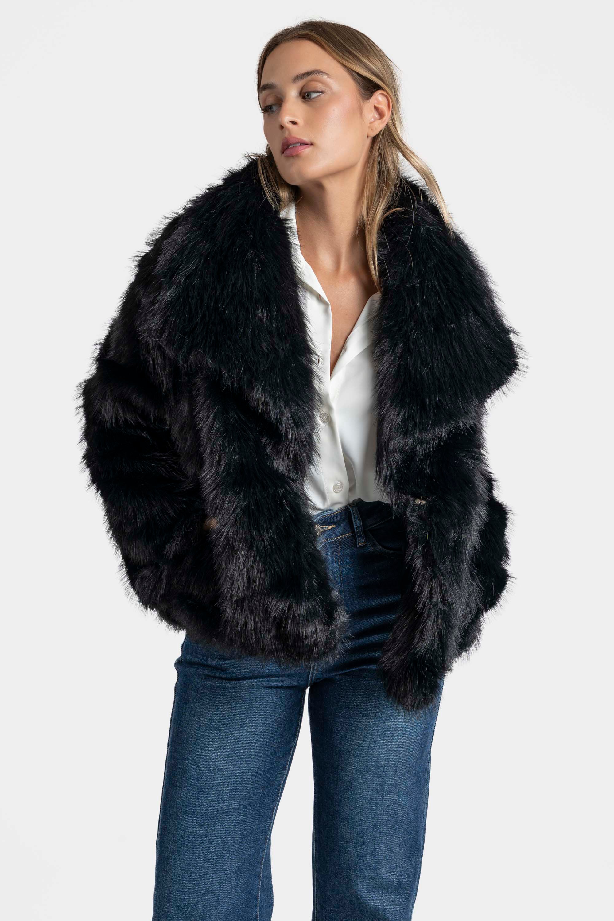 Modèle en Veste fausse fourrure noire, style oversized, offrant confort et élégance, parfaite pour les journées fraîches.