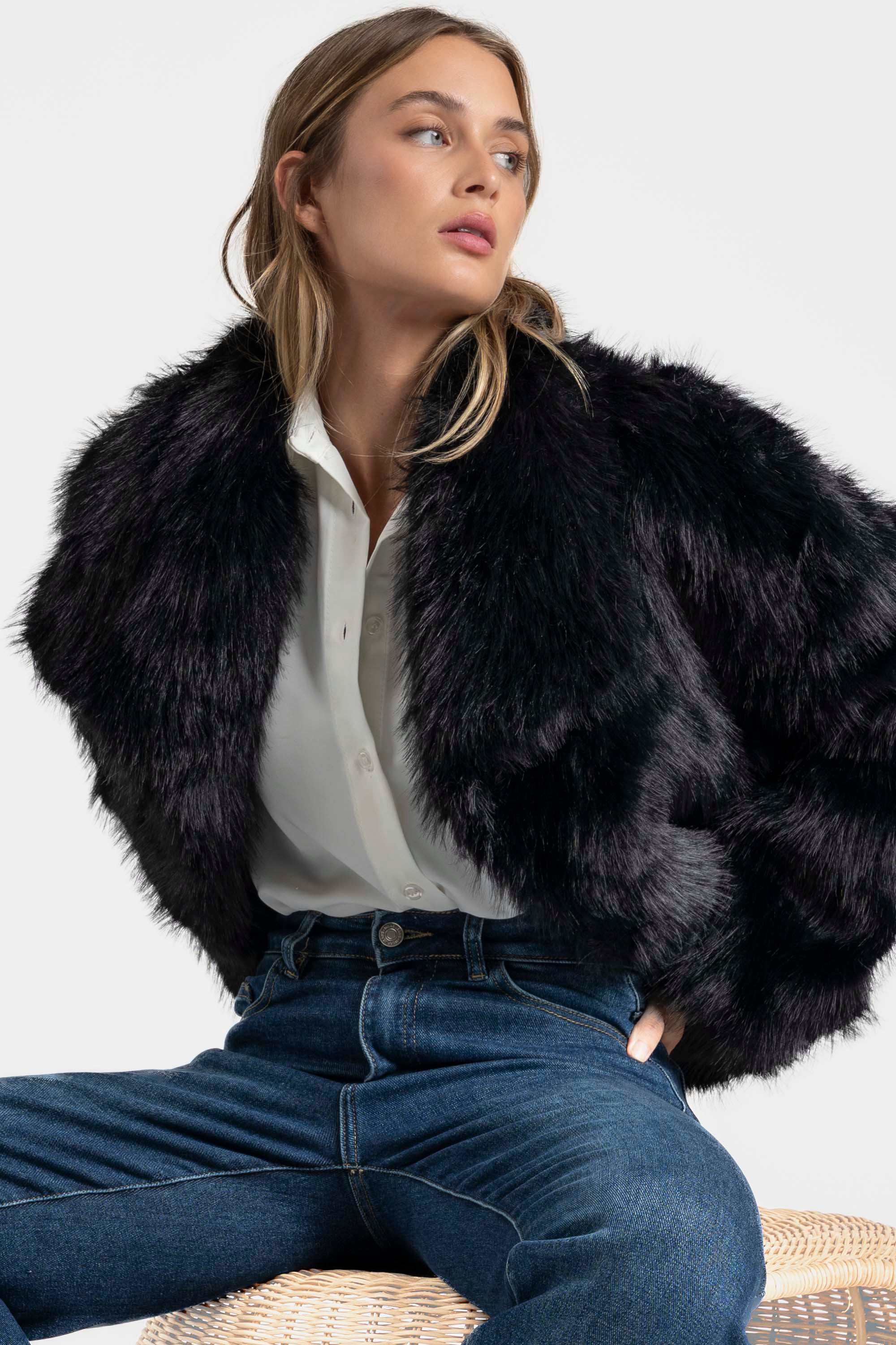 Femme posant dans une Veste fausse fourrure noire, ajoutant une touche chic à un look décontracté.