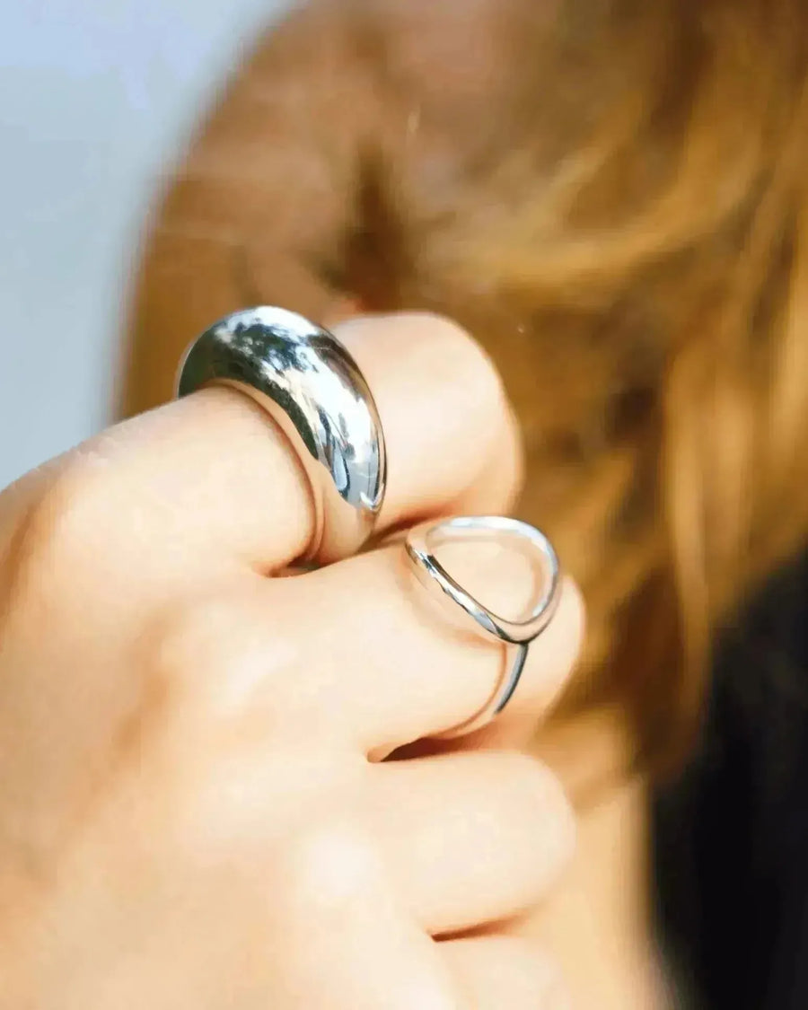 Gros plan sur des doigts portant des bagues, y compris une bague argentée femme. La bague argentée femme complète parfaitement le style moderne et chic.