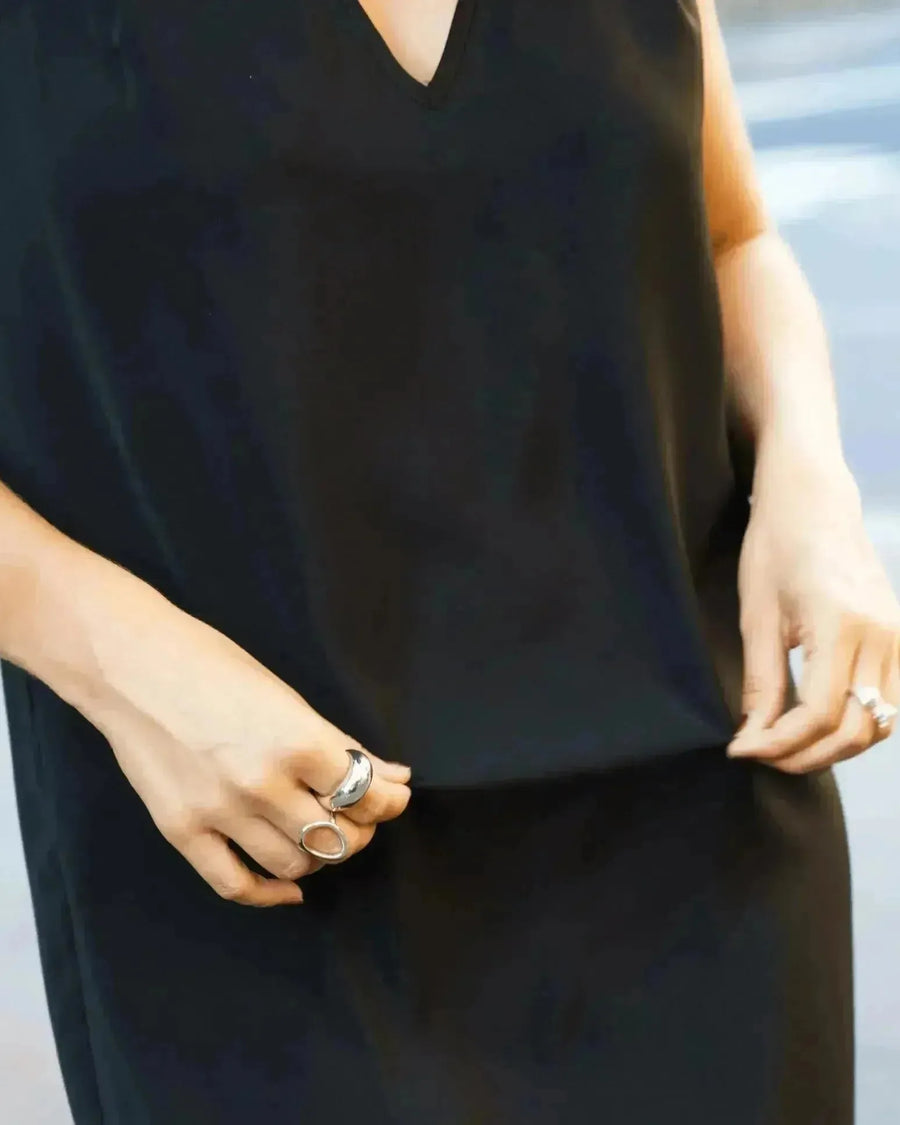 Une femme portant une robe noire élégante, mettant en avant sa bague argentée femme. Cette bague argentée femme ajoute une touche de sophistication à son look.