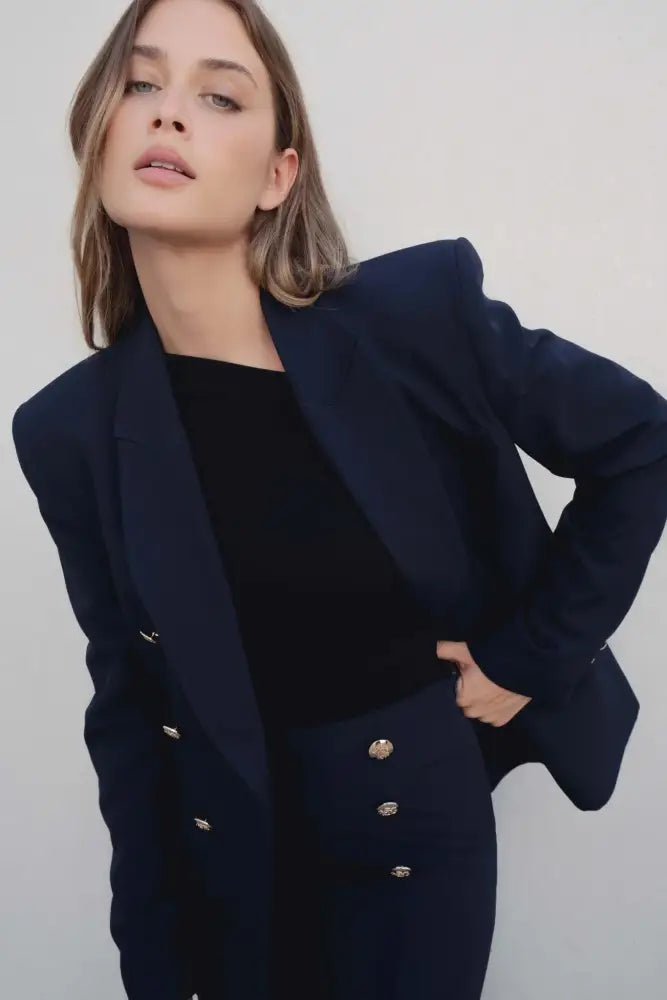 Femme portant un blazer femme bleu marine à boutons dorés et épaulettes prononcées