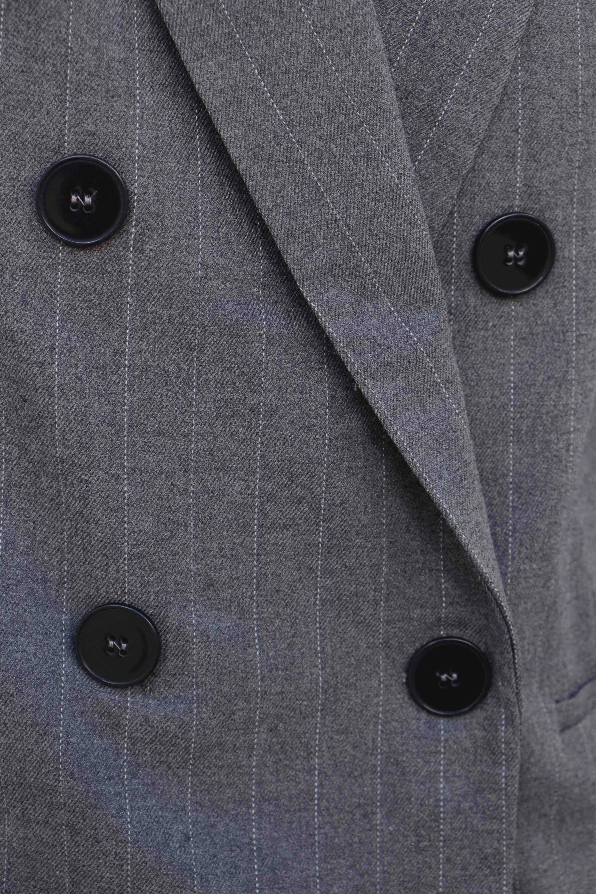 Zoom sur le double boutonnage du blazer femme chic gris à rayures fines, soulignant son élégance et sa sophistication.