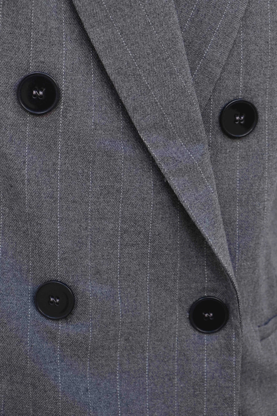 Zoom sur le double boutonnage du blazer femme chic gris à rayures fines, soulignant son élégance et sa sophistication.