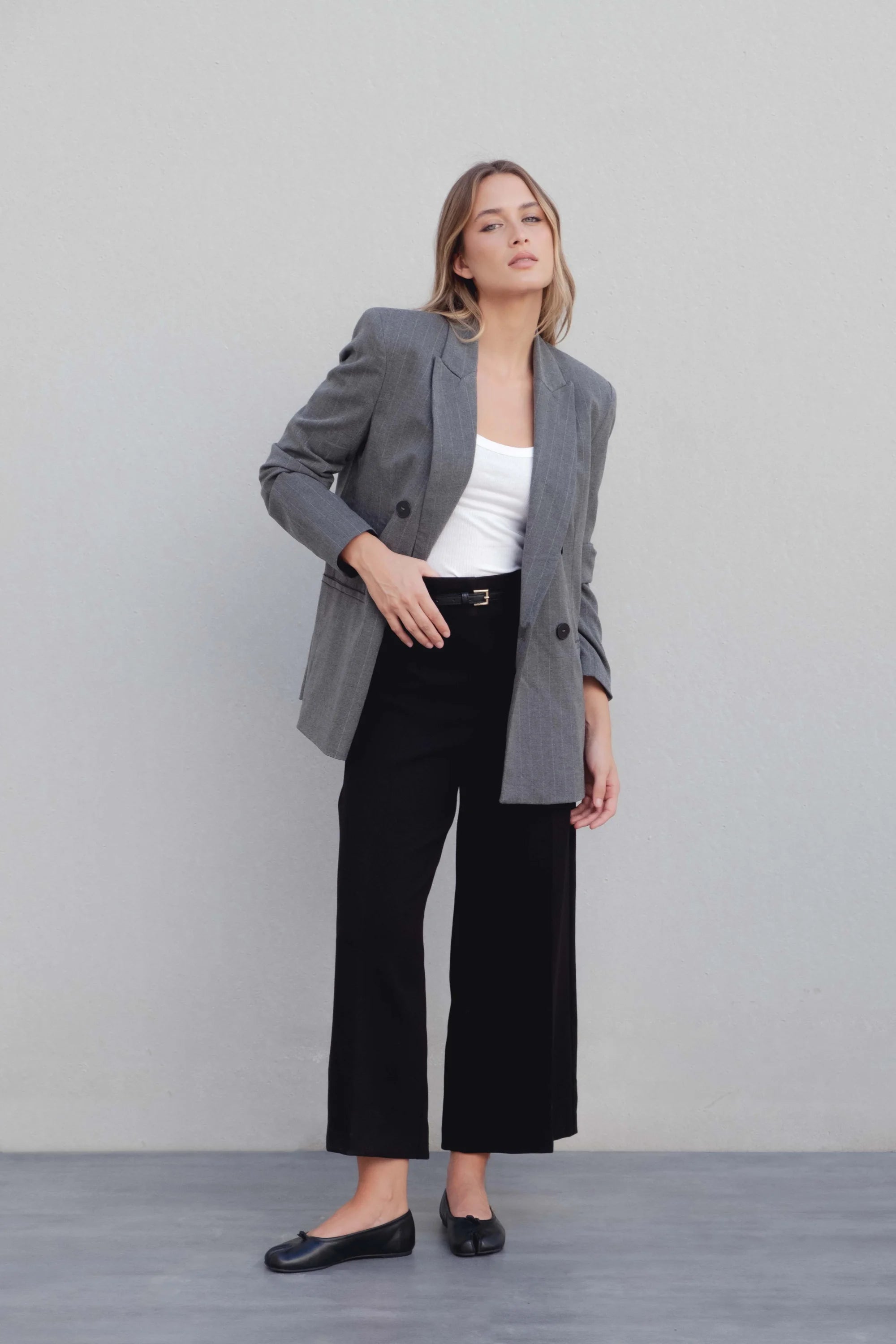 Modèle portant un blazer femme chic gris à rayures fines avec un pantalon noir, illustrant le style moderne et élégant.