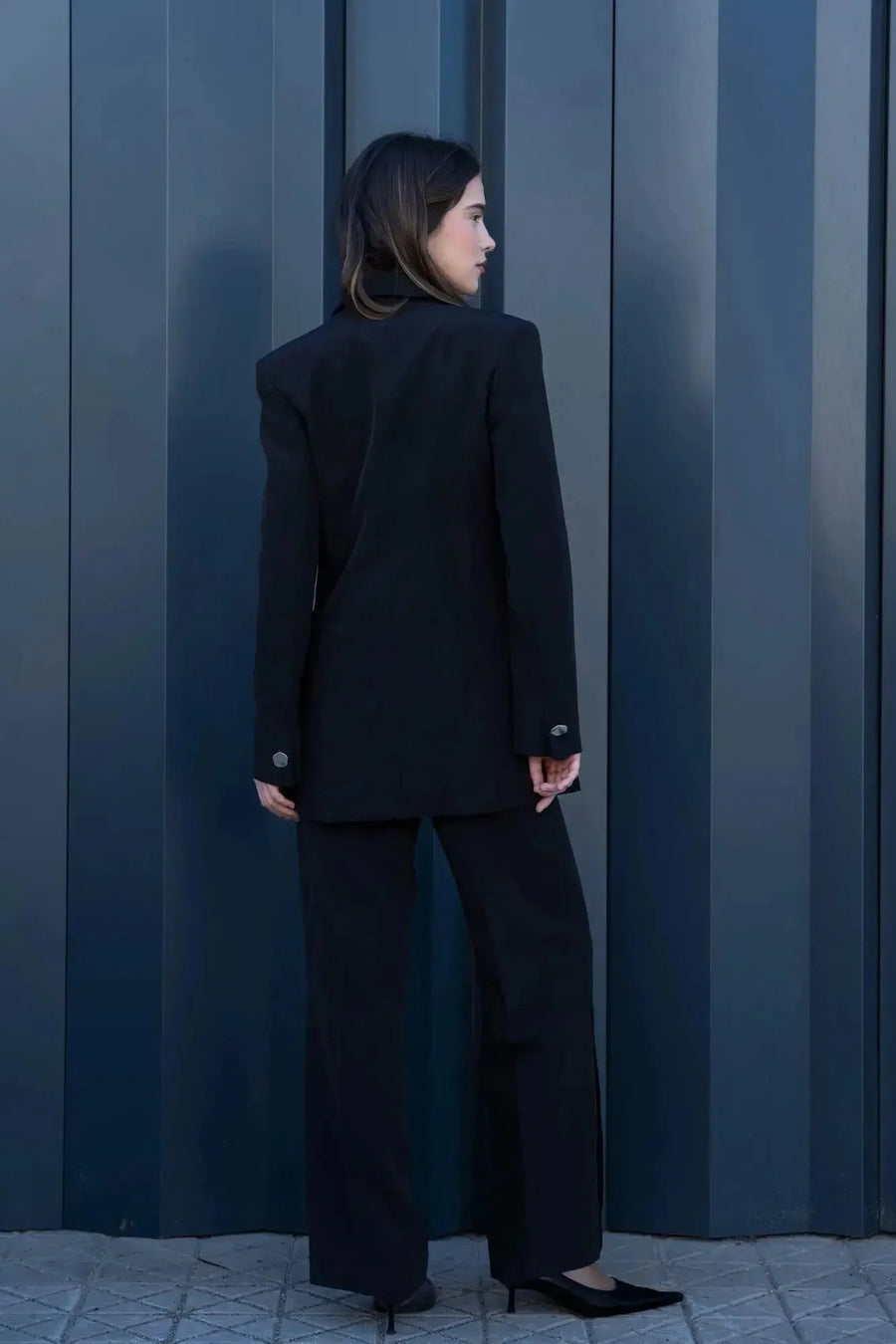 Vue arrière d'un modèle portant le Blazer Femme Noir à Boutons Argentés, montrant la coupe élégante et contemporaine du blazer chic femme.