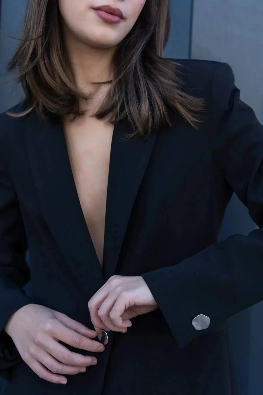 Détails du Blazer Femme Noir à Boutons Argentés, avec un modèle ajustant la boutonnière, soulignant la sophistication de ce blazer chic femme.