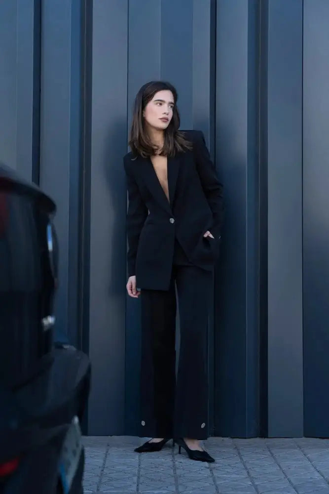 Femme portant un blazer noir à boutons argentés et talons élégants