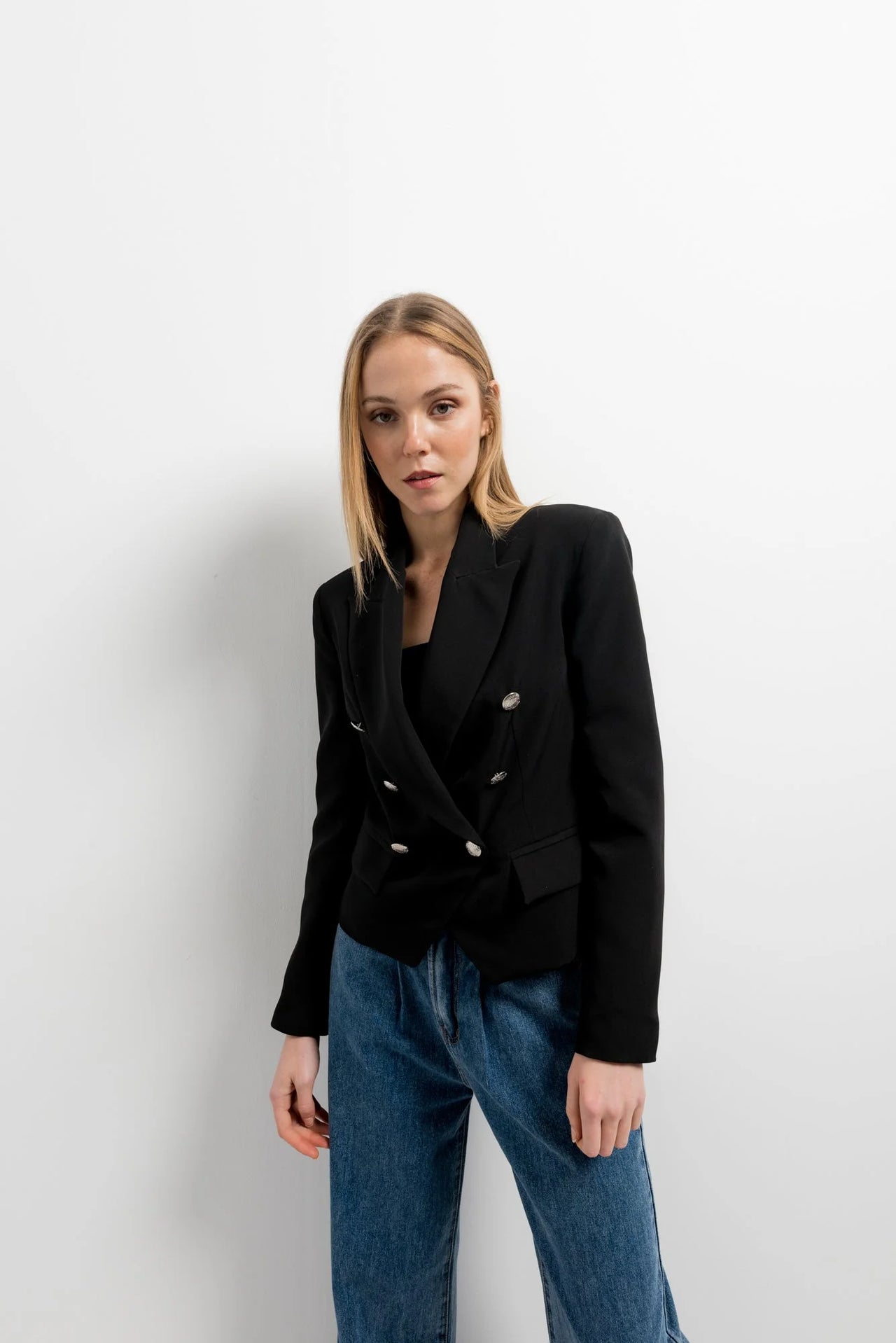 Femme portant une veste blazer noir femme boutonnée à double poitrine, associée à un pantalon décontracté, idéale pour un look moderne et élégant.