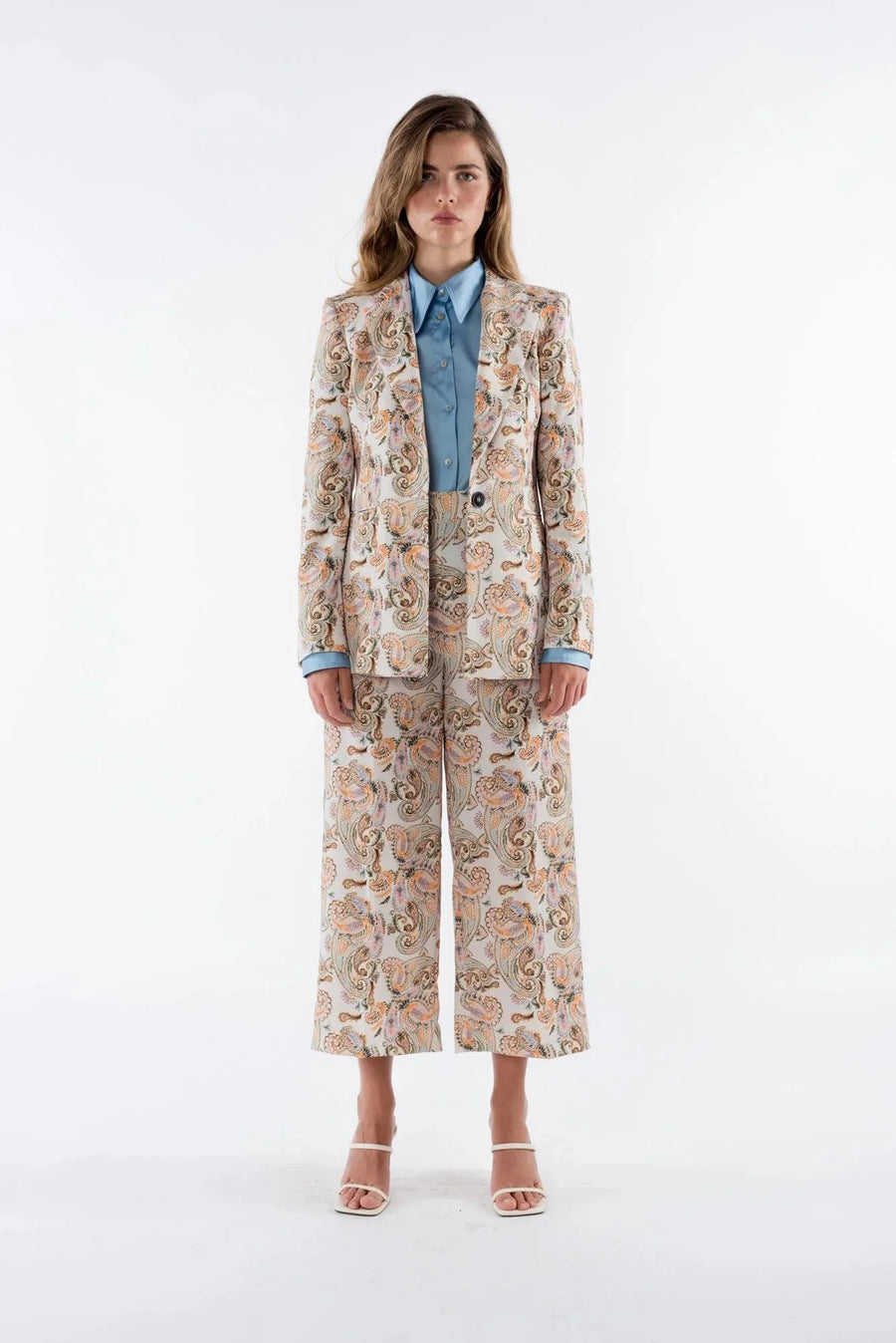Présentation complète d'un blazer femme imprimé paisley beige, associé à un chemisier bleu, mettant en valeur les détails raffinés de ce blazer fleuri femme.