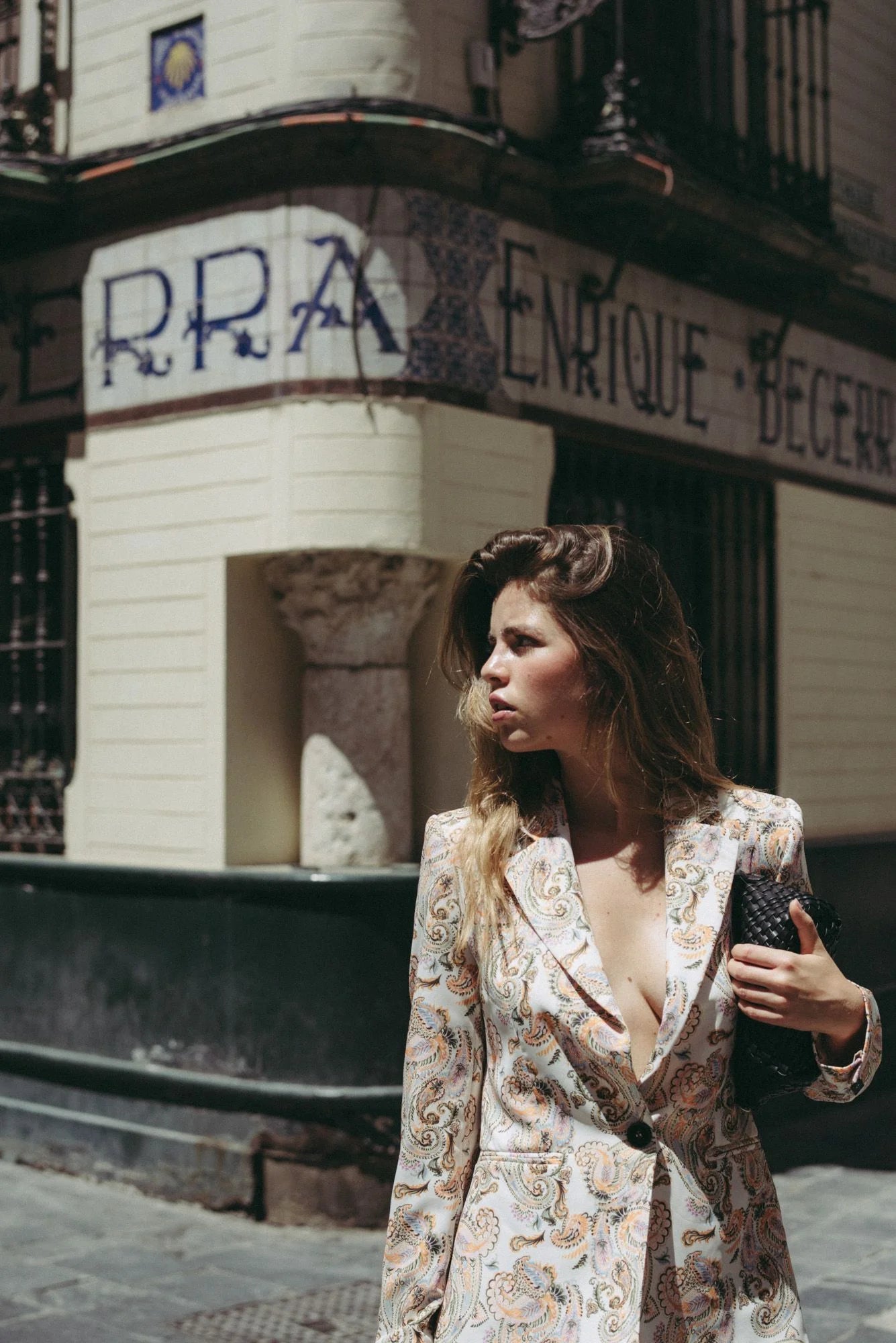 Femme stylée en blazer femme imprimé paisley beige, posant avec assurance dans une rue, illustrant l'originalité du blazer fleuri femme.