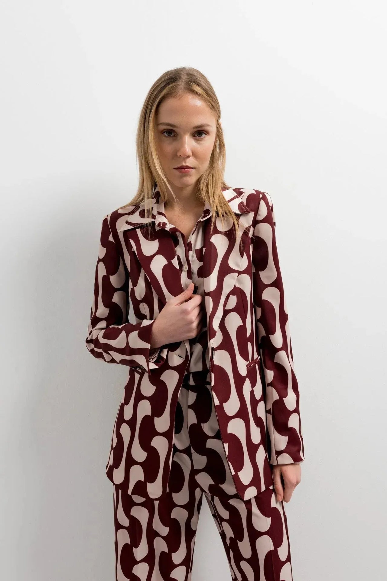 Femme portant un blazer imprimé tendance femme chic avec un motif graphique, regard serein, montrant le style contemporain du blazer motif femme.