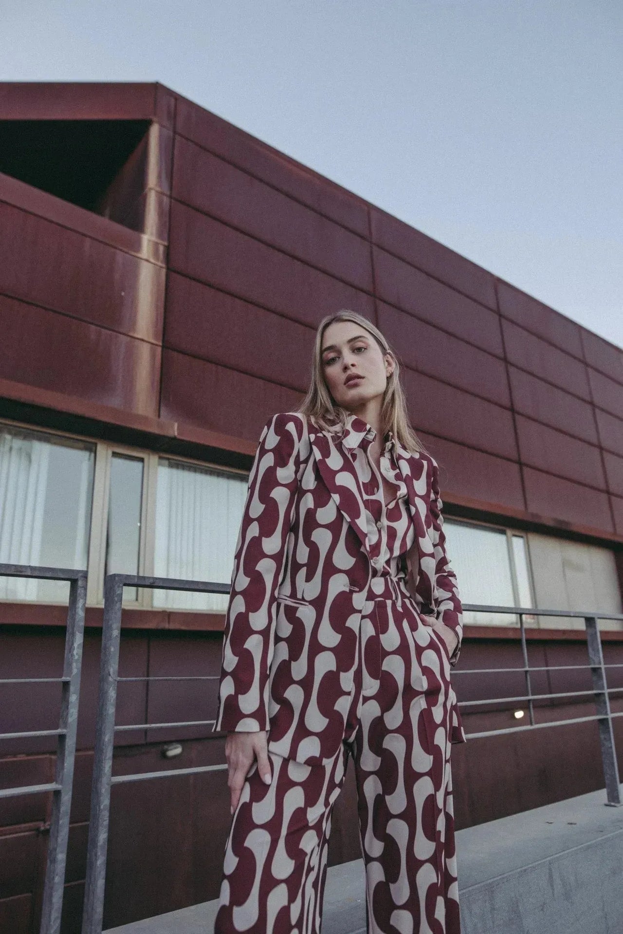 Femme dans un blazer imprimé tendance femme chic, avec un motif unique, posant dans un décor moderne pour illustrer le chic du blazer motif femme.