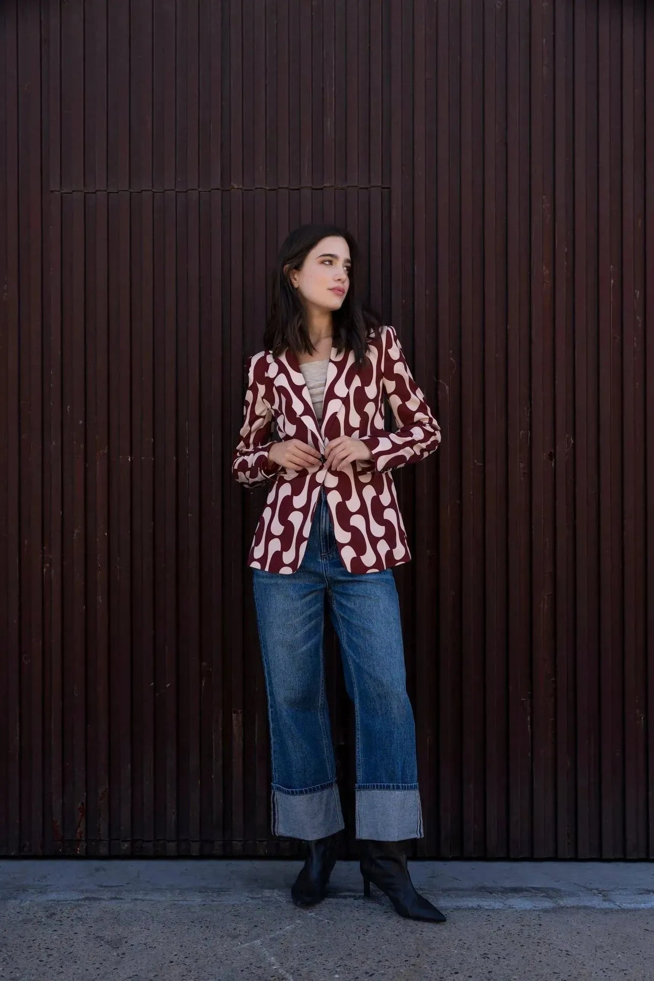 Vue profil d'une femme en blazer imprimé tendance femme chic avec un motif contemporain, associée à un haut beige et un jean, soulignant le style unique du blazer motif femme.