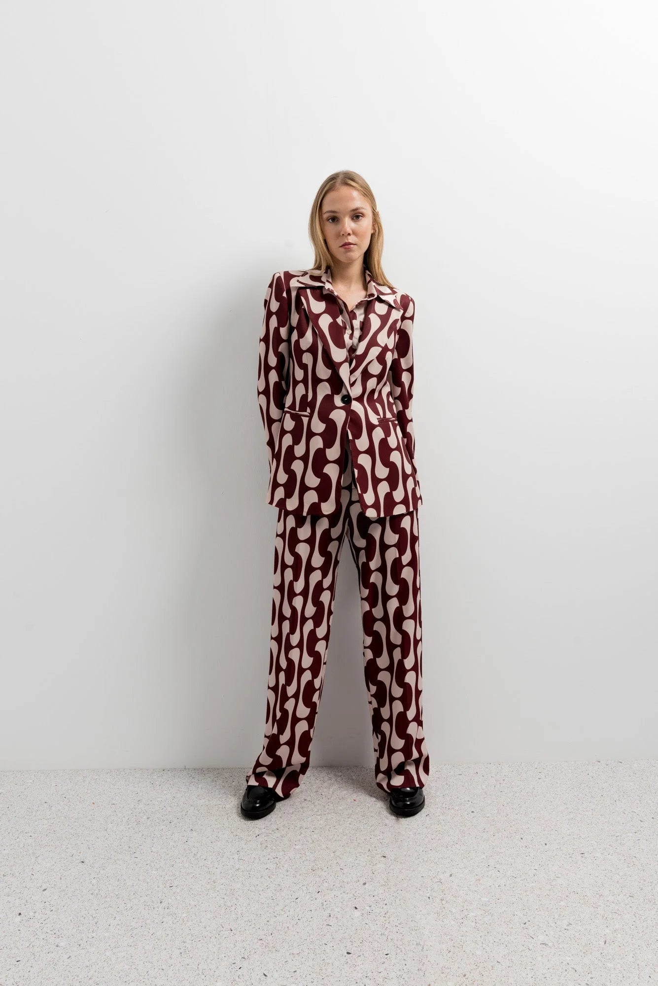 Femme en costume complet avec un blazer imprimé tendance femme chic, présentant un motif graphique, mettant en avant le style audacieux du blazer motif femme.