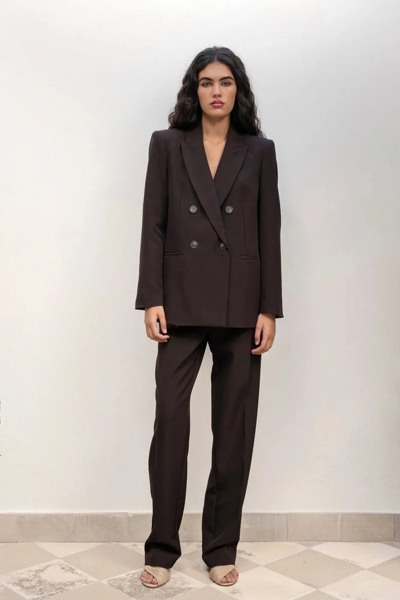 Femme debout avec un blazer double boutonnage femme oversize et un pantalon assorti, montrant une allure moderne et élégante.
