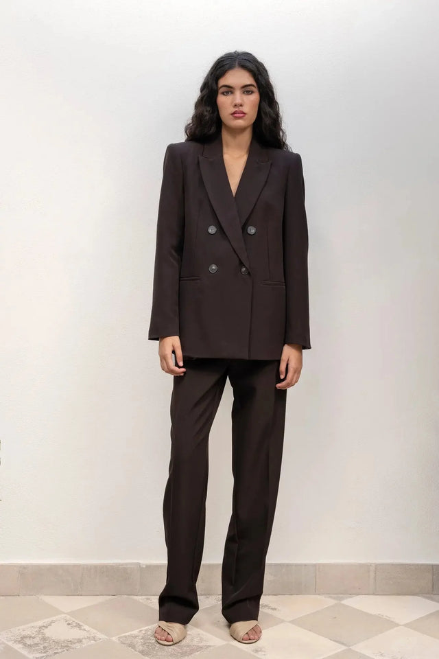 Femme debout avec un blazer double boutonnage femme oversize et un pantalon assorti, montrant une allure moderne et élégante.