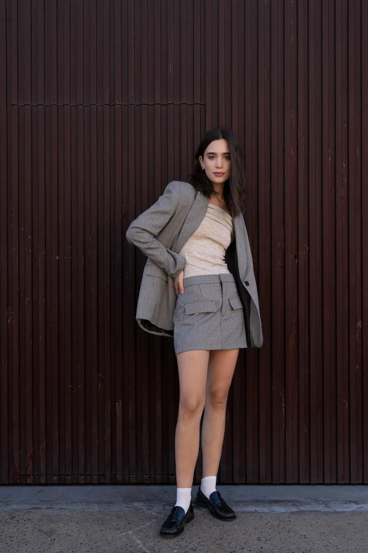 Femme portant un blazer pied-de-poule gris et une mini jupe, style élégant