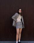 Femme portant un blazer pied-de-poule gris et une mini jupe, style élégant