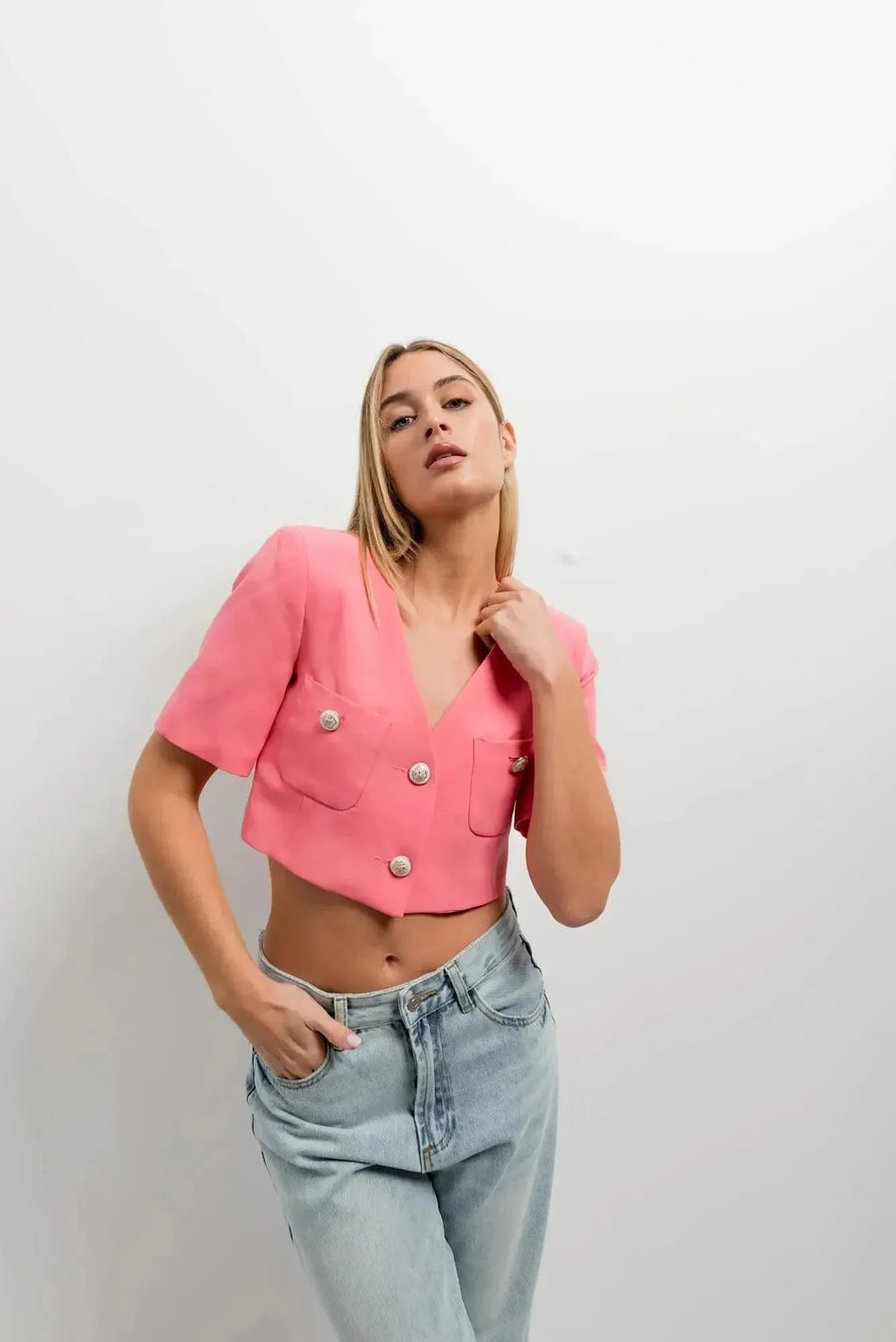Femme portant un blazer recadré rose à manches courtes, associé à un haut décontracté, style chic et moderne, blazer crop top.