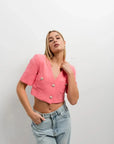 Femme portant un blazer recadré rose à manches courtes, associé à un haut décontracté, style chic et moderne, blazer crop top.