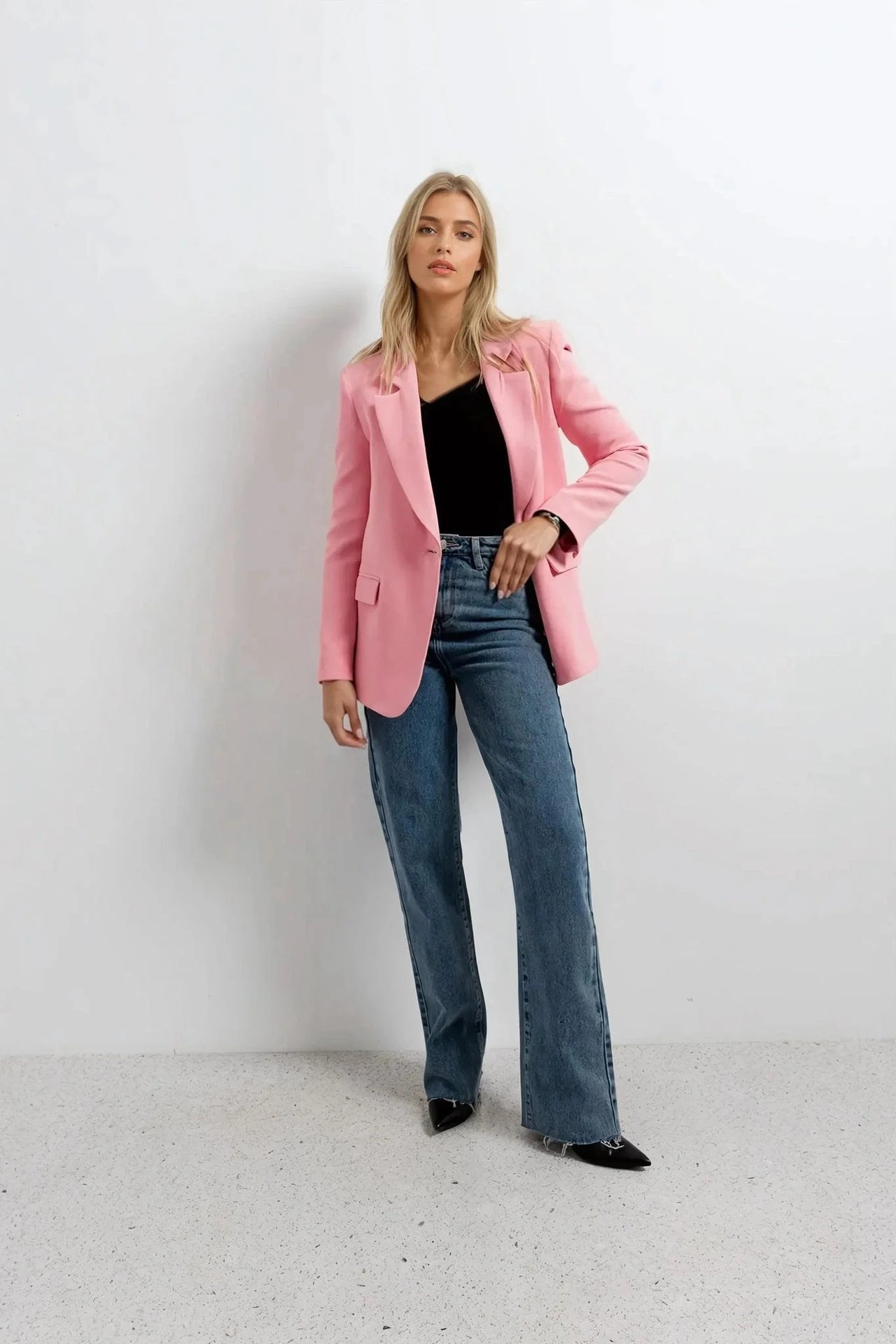Blazer rose femme au confort inégalé porté avec un t-shirt noir et un jean, alliant élégance et style décontracté.