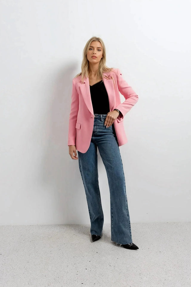 Blazer rose femme au confort inégalé porté avec un t-shirt noir et un jean, alliant élégance et style décontracté.