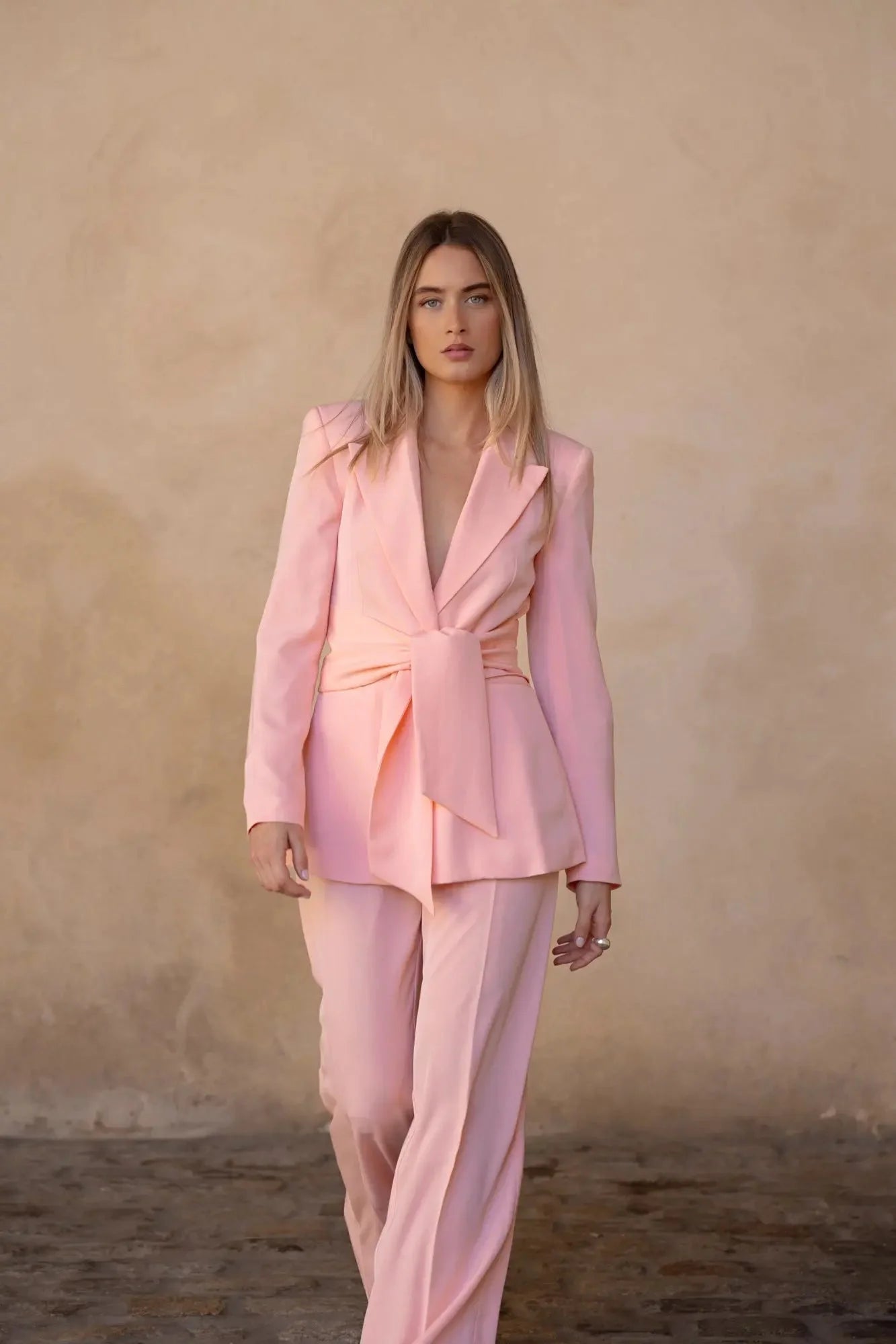 Femme marchant avec assurance dans un Blazer Rose Femme Ceinturé, ajoutant une touche de modernité à sa silhouette.