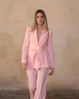 Femme marchant avec assurance dans un Blazer Rose Femme Ceinturé, ajoutant une touche de modernité à sa silhouette.