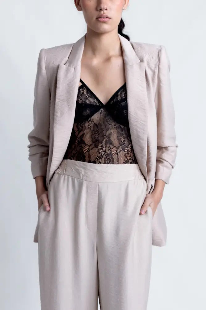 Femme portant un blazer texturé beige, camisole en dentelle noire et pantalons décontractés