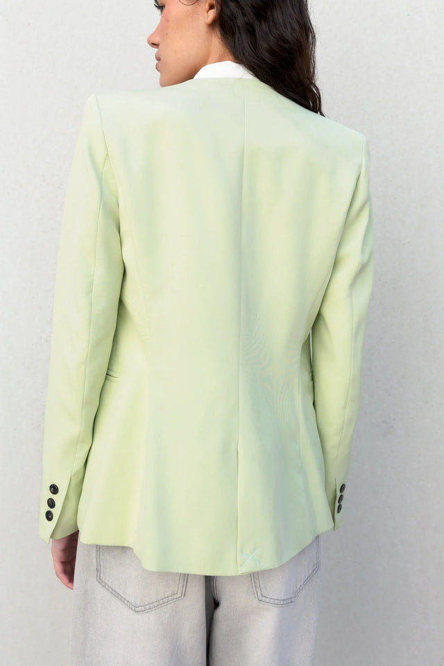 Détails de l'arrière d'une veste vert pastel femme sans col, montrant la coupe élégante et moderne.