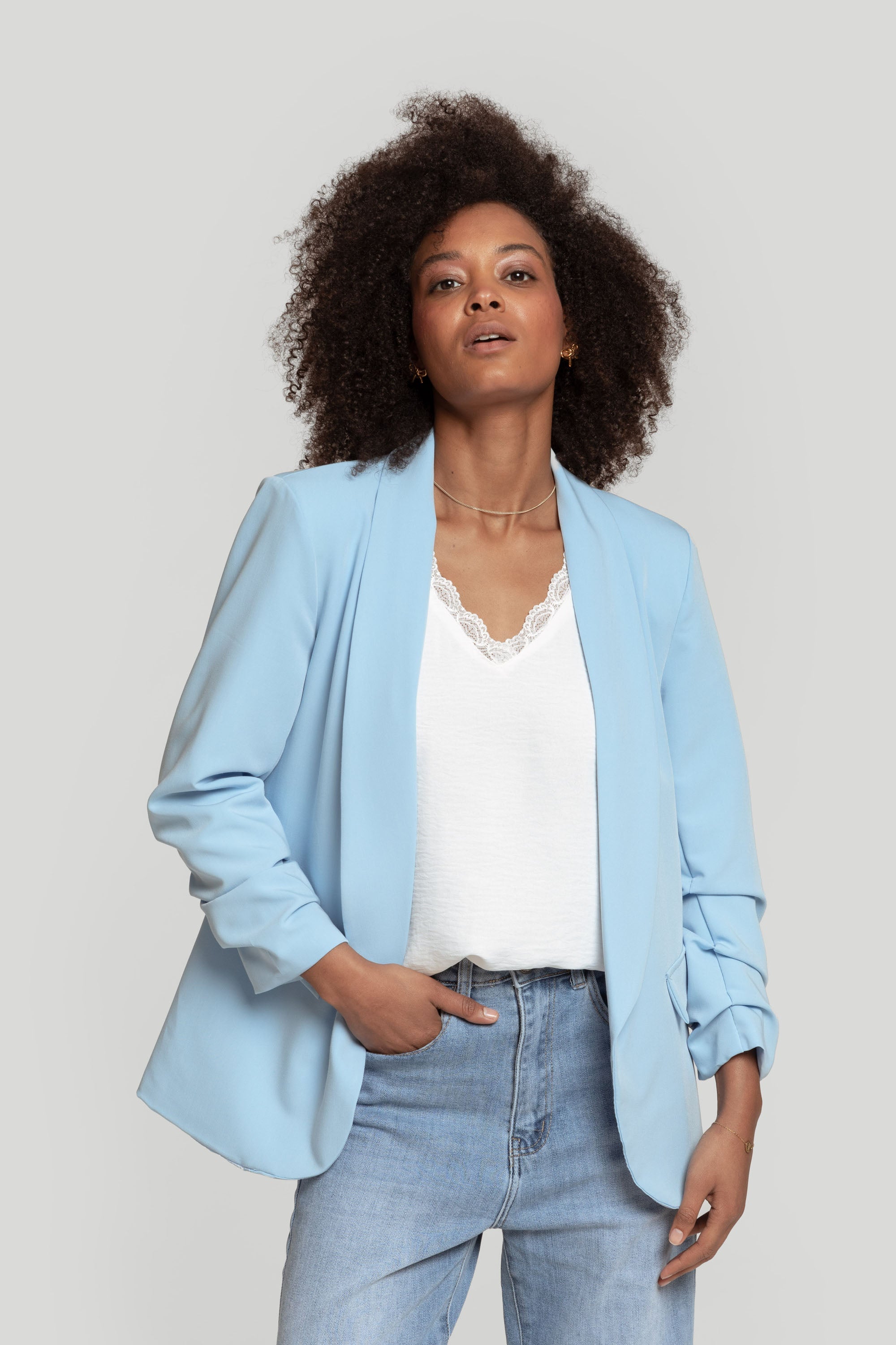 Femme dans un blazer femme chic bleu clair, avec un haut décontracté et un jean.