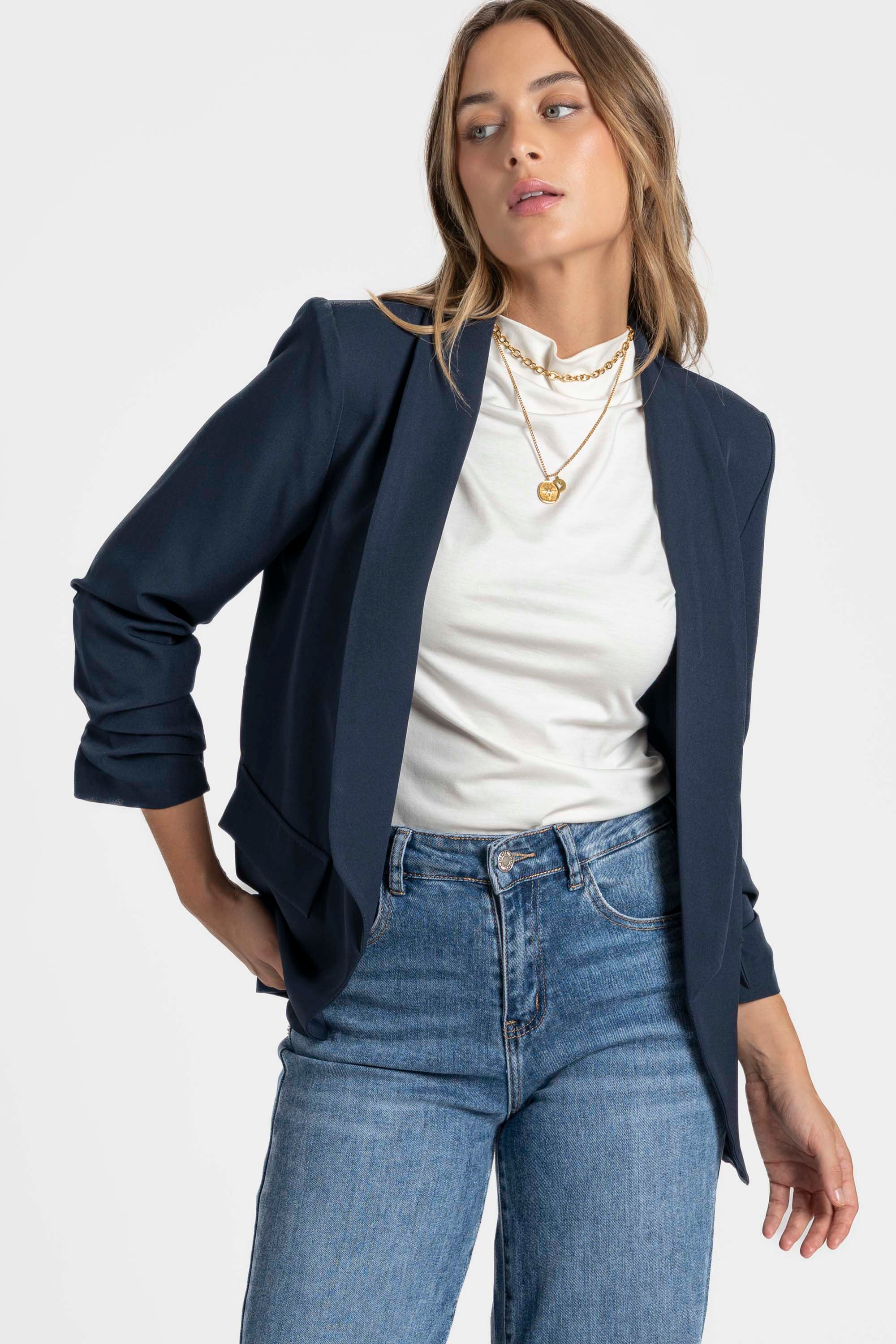 Femme affichant un blazer femme chic bleu marine, bien ajusté sur un décolleté blanc.