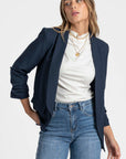 Femme affichant un blazer femme chic bleu marine, bien ajusté sur un décolleté blanc.