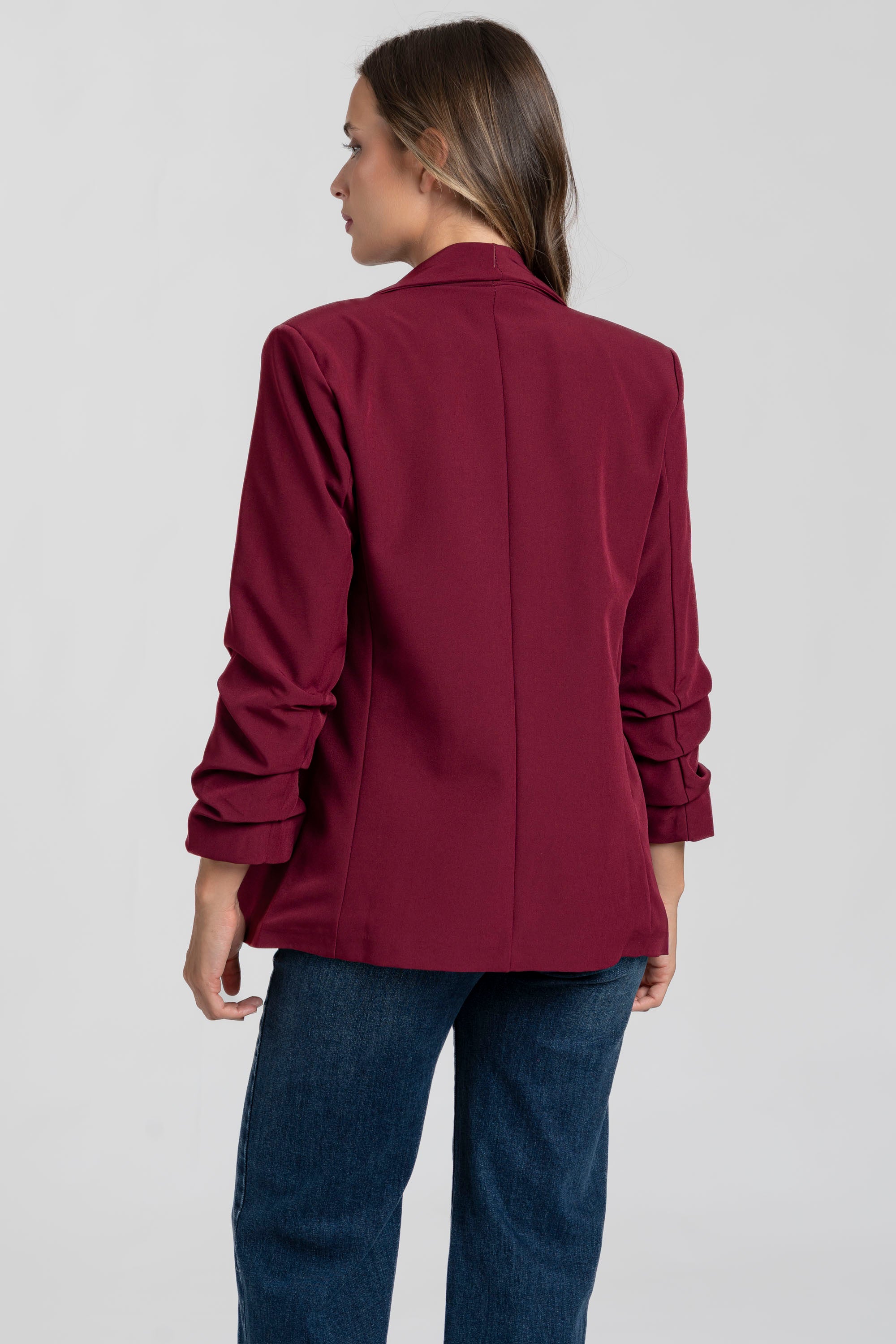 Femme portant un blazer femme chic bordeaux en vue arrière, affichant une silhouette moderne et élégante.